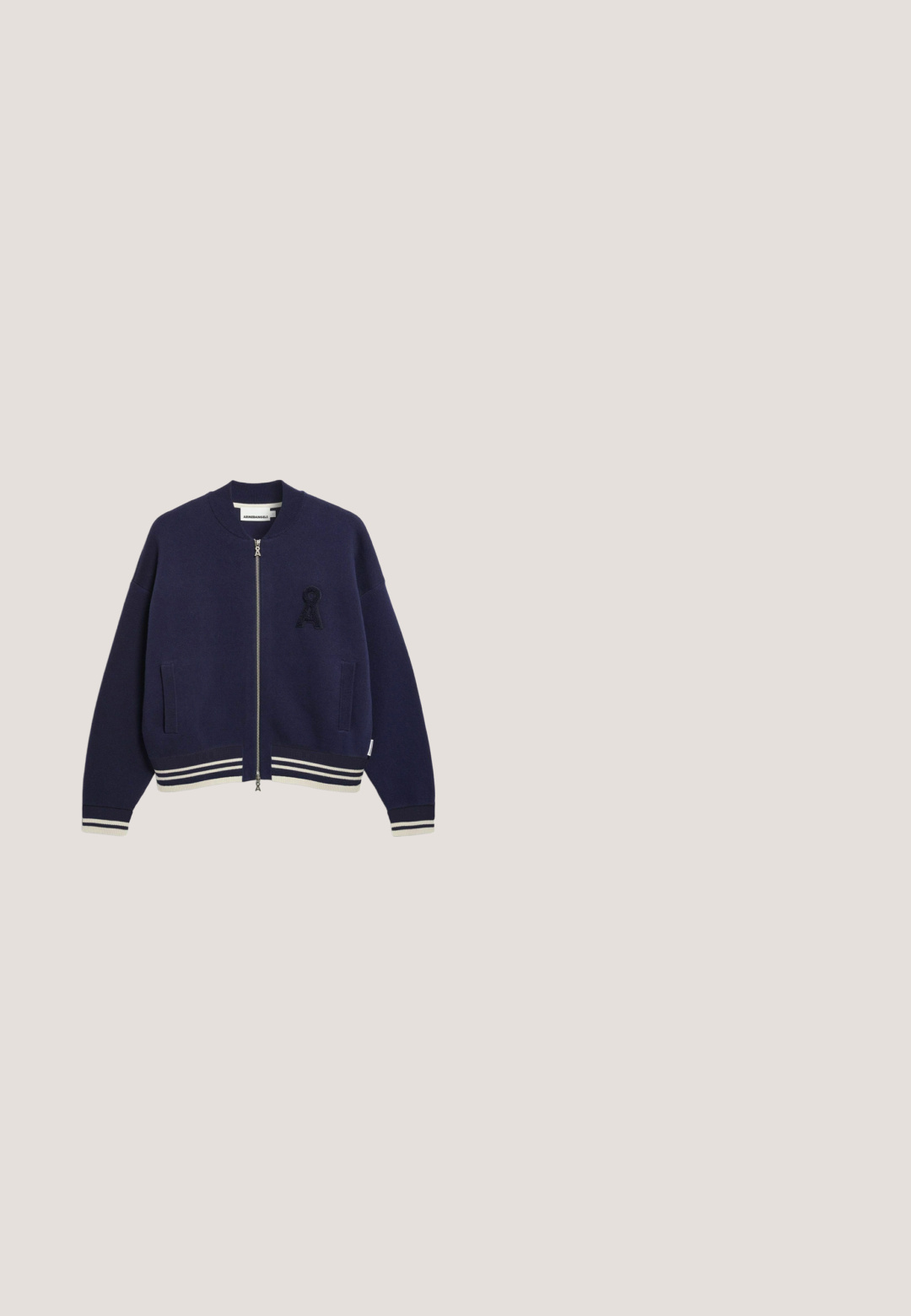 Marineblauwe bomberjas met een ritssluiting aan de voorkant, geribbelde manchetten en wit gestreepte bies. Voorzien van een getextureerd 'A'-logo op het linkerborstzakje.; Donkerblauw langemouwen cropped shirt met ronde hals, plat weergegeven op een witte achtergrond.; Zwarte broek met wijde pijpen, elastische tailleband en dunne witte zijstrepen, plat gelegen op een witte achtergrond.; Lage zwart-witte sneaker met rubberen zool, roze veters, decoratieve zijstiksels en wit hielaccent, zijaanzicht.; Pofzak in halvemaanvorm in marineblauw met zwart-wit gestreepte verstelbare schouderriem en ritssluiting.; Zilveren armband met een delicate schakelontwerp met rechthoekige schakels en een kreeftsluiting. Inclusief een kleine schelpencharme als accent.