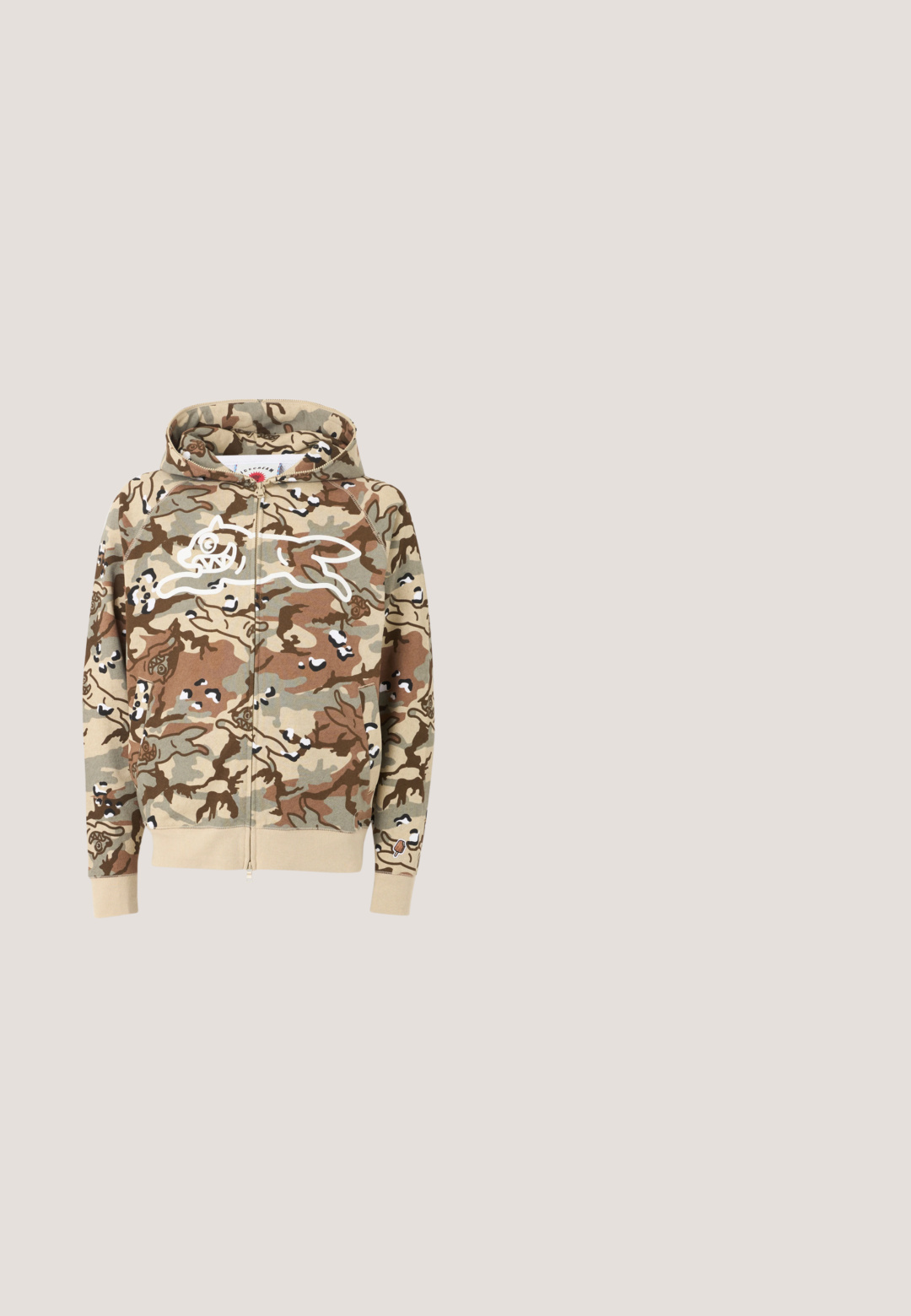 Sudadera con capucha con cremallera en camuflaje beige, marrón y verde con contorno blanco en la parte delantera de un perro de dibujos animados corriendo y puños y cinturilla beige.; Camiseta de manga corta camuflaje beige y marrón claro con logo blanco "Aries" y diseño de columna en el pecho izquierdo.; Pantalones de chándal de camuflaje con un patrón natural en tonos marrón y verde, que cuentan con una cintura elástica con cordón y puños elásticos en los tobillos.; Bota de cuero marrón de corte medio con suela de goma texturizada verde, entresuela beige, ojales metálicos y detalle negro en el talón. Costuras detalladas en el cuerpo.; Gafas de sol de plástico verde con montura rectangular, lentes marrones con degradado y una sutil marca en las patillas. Superficie texturizada en la montura.; Bolsa tote con patrón de camuflaje hecha de tela texturizada con dos asas. Cuenta con un logotipo blanco prominente en un lado.