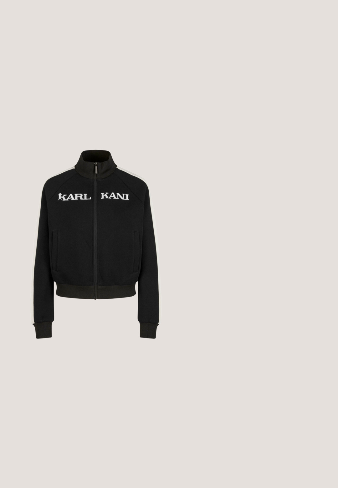 Chaqueta negra con cremallera y cuello alto, con franjas laterales blancas y el logo "KARL KANI" en letras grandes en el pecho. Textura de tejido suave.; Top crop blanco de manga larga hecho de tela acanalada, con un logotipo negro característico en el pecho. Cuello redondo y diseño ceñido.; Pantalones de chándal negros y de pierna ancha, fabricados en un tejido suave, con una cinturilla elástica con cordones y un acento del logo en blanco.; Zapatillas deportivas blancas con acentos grises, que cuentan con un Upper texturizado, perforaciones para ventilación y un talón segmentado para amortiguación.; Bolso de mano negro con un suave borde de piel sintética blanca, con forma redondeada y cierre de cremallera. Logo "KARL LAGERFELD JEANS" exhibido de forma prominente.; Collar choker de malla plateada con un diseño elegante y flexible. Incluye un cierre de langosta y una cadena de extensión para ajustar la longitud.