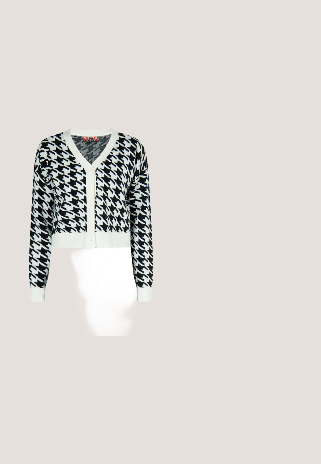 Cardigan à motif pied-de-poule noir et blanc, manches longues boutonnées, bordures blanches et poignets ajustés, présenté sur un fond uni.; Polo blanc à manches courtes en maille côtelée avec bord festonné noir sur le col et la patte de boutonnage, étiquette de marque à l'intérieur du col.; Pantalons à jambes larges en motif carreaux noir et beige, avec une taille élastique et une texture de tissu douce.; Bottine à imprimé vache avec une finition texturée, un bout pointu et un talon épais noir. Conçue à partir d'un matériau doux avec un motif unique.; Sac à main matelassé noir décoré d'yeux dessinés, un cœur, un œuf au plat, une fermeture éclair décorative et des pins avec les textes "NON" et "Oui !".; Boucles d'oreilles puces en forme de cœur doré, avec deux cœurs empilés, gravés de "CPH STUDIOS" sur les cœurs les plus grands.
