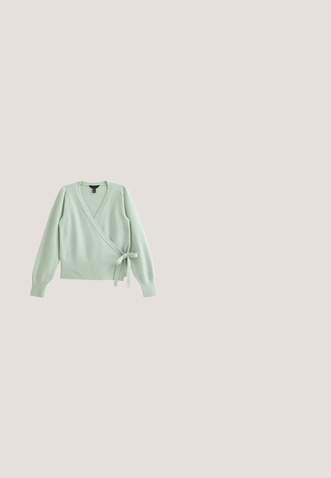 Suéter envolvente verde claro con mangas largas, acabado texturizado, dobladillo acanalado y cierre de lazo en la cintura. Fabricado con un material suave y cálido.; Blusa blanca de manga larga, con un patrón floral texturizado, escote fruncido y puños elásticos. Tejido suave y ligero.; Falda larga con pliegues en suave tela rosa, que presenta una cintura elástica. La textura suave y el diseño fluido realzan su forma general.; Bailarinas de charol rosa con punta redondeada, detalle de cuerda en la parte delantera y suela de goma beige. Acabado liso y brillante en todo.; Bolso bandolera de cuero rosa con correa de cadena dorada y cierre rectangular dorado sobre fondo blanco.; Gran coletero de raso rosa con textura suave y brillante y un pequeño detalle de anillo dorado en el centro elástico.