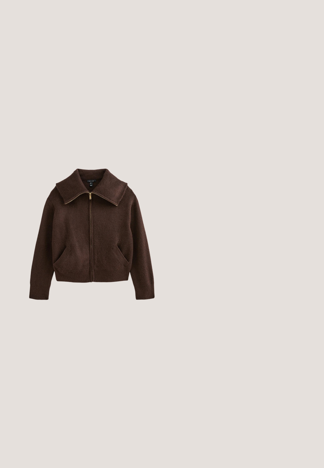 Brun fleece zip-up jakke med stor krave, to frontlommer og guld lynlåsdetaillering. Blød tekstur, cropped design.; Brun kortærmet top med asymmetrisk halsudskæring, samlet og fastgjort på den ene skulder med en lille metalclips.; Brune viddebukser i en bomuldsblanding, med en frynset kant, frontknaplukning og klassisk fem-lomme design. Minimalistiske og alsidige.; Mørkebrune læder ankelstøvler med spids tå og stakket blokhæl, glat finish og minimal syning.; Brun ruskindstaske med læderdetailler, dobbelte stropper og lynlåslomme foran. Har guldfarvet hardware og en glat tekstur.; Rings med ravfarvet harpiks i en glat, rund form. Har et sølvbånd for sikker pasform. Gennemsigtig med lette farvevariationer.
