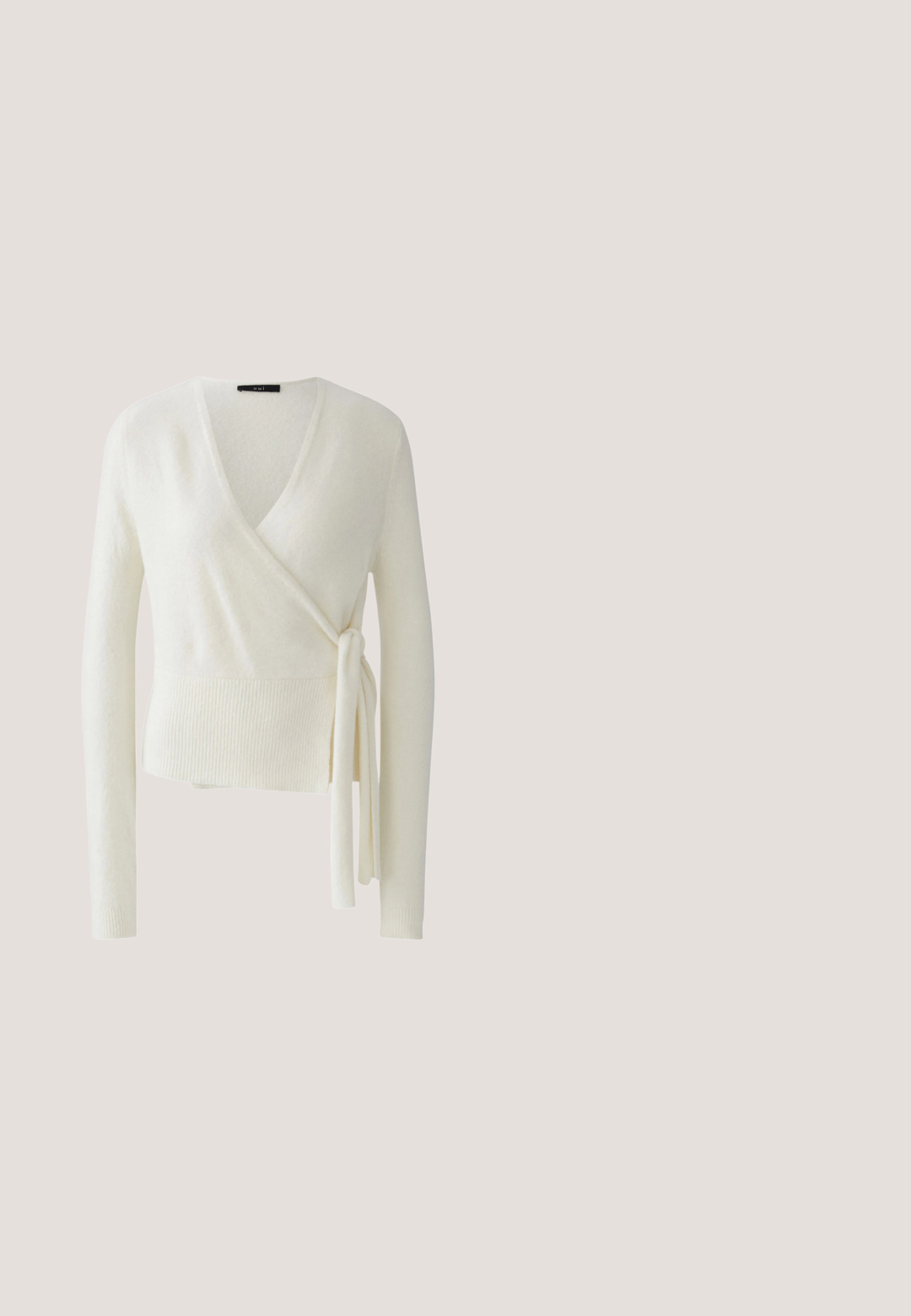 Witte wikkeltrui met lange mouwen, V-hals en zijstrikdetail, geribde zoom en manchetten, zachte gestructureerde stof.; Beige body met lange mouwen en een ontwerp met één schouder. Heeft een geplooide textuur, hoog uitgesneden pijpen en zachte, rekbare stof.; Lichtbeige tule stof met een zachte, doorschijnende textuur, met een fijne gaasweving die zachte golven en plooien creëert.; Beige suède balletschoen met een lichtpuntige neus, een strikaccent aan de voorkant en een klein metallic logo op de hak. Platte zool.; Lichtroze leren crossbodytas met een afgeronde klep, gouden metalen sluiting met drukknop en een dunne verstelbare riem. Gladde textuur.; Lichtroze satijnen scrunchie met een klein beige label op een witte achtergrond, met een gladde, glanzende stof en geraffineerde textuur.