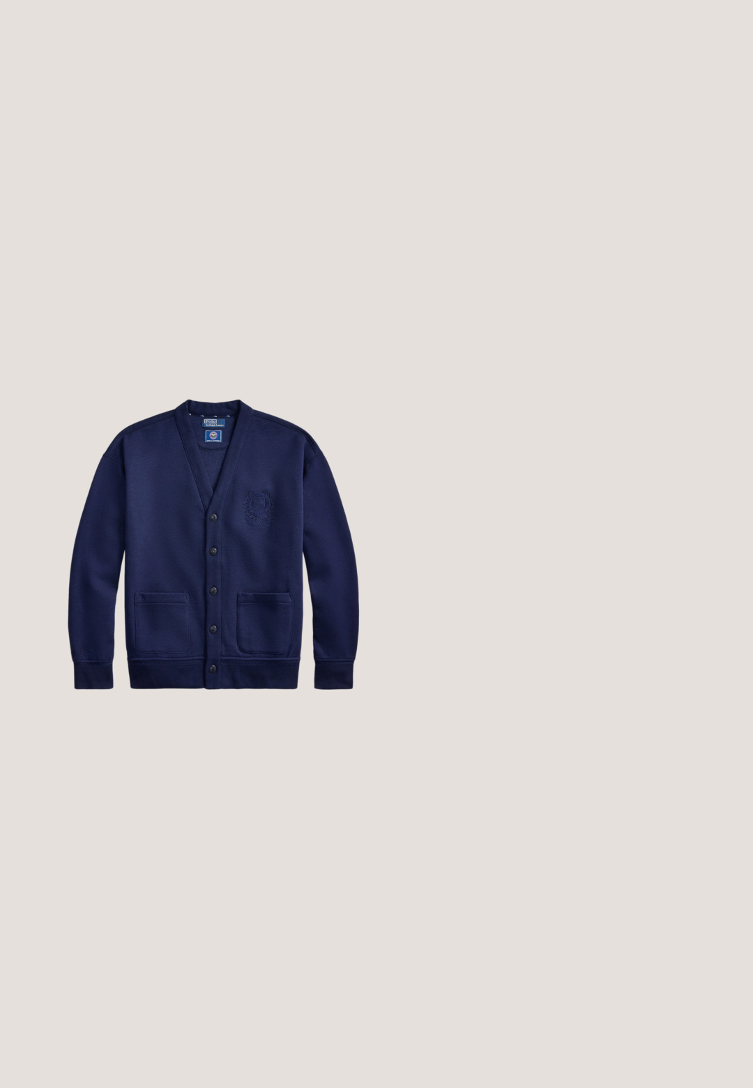 Marineblauer Cardigan mit Knopfleiste vorne, zwei Taschen und gesticktem Wappen auf der linken Brust, beschriftet Polo von Ralph Lauren.; Weißes Poloshirt mit kurzen Ärmeln, Kragen, Zwei-Knopf-Leiste und kleinem dunkelblauem Logo auf der linken Brust.; Hellbeige gerade Hose mit Eingrifftaschen, Gürtelschlaufen und Knopfverschluss, flach auf weißem Hintergrund dargestellt.; Blauer Wildleder-Slipper mit weißer Sohle und beiger Naht am oberen Rand, dargestellt vor einem schlichten weißen Hintergrund.; Marineblaue Tragetasche mit schwarzen Griffen und verstellbarem Schultergurt, mit kleinem silbernem Polo-Spieler-Logo mittig auf der Vorderseite.; Schwarzer strukturierter Ledergürtel mit einer silbernen rechteckigen Metallschnalle, aufgerollt auf einem hellgrauen Hintergrund dargestellt.
