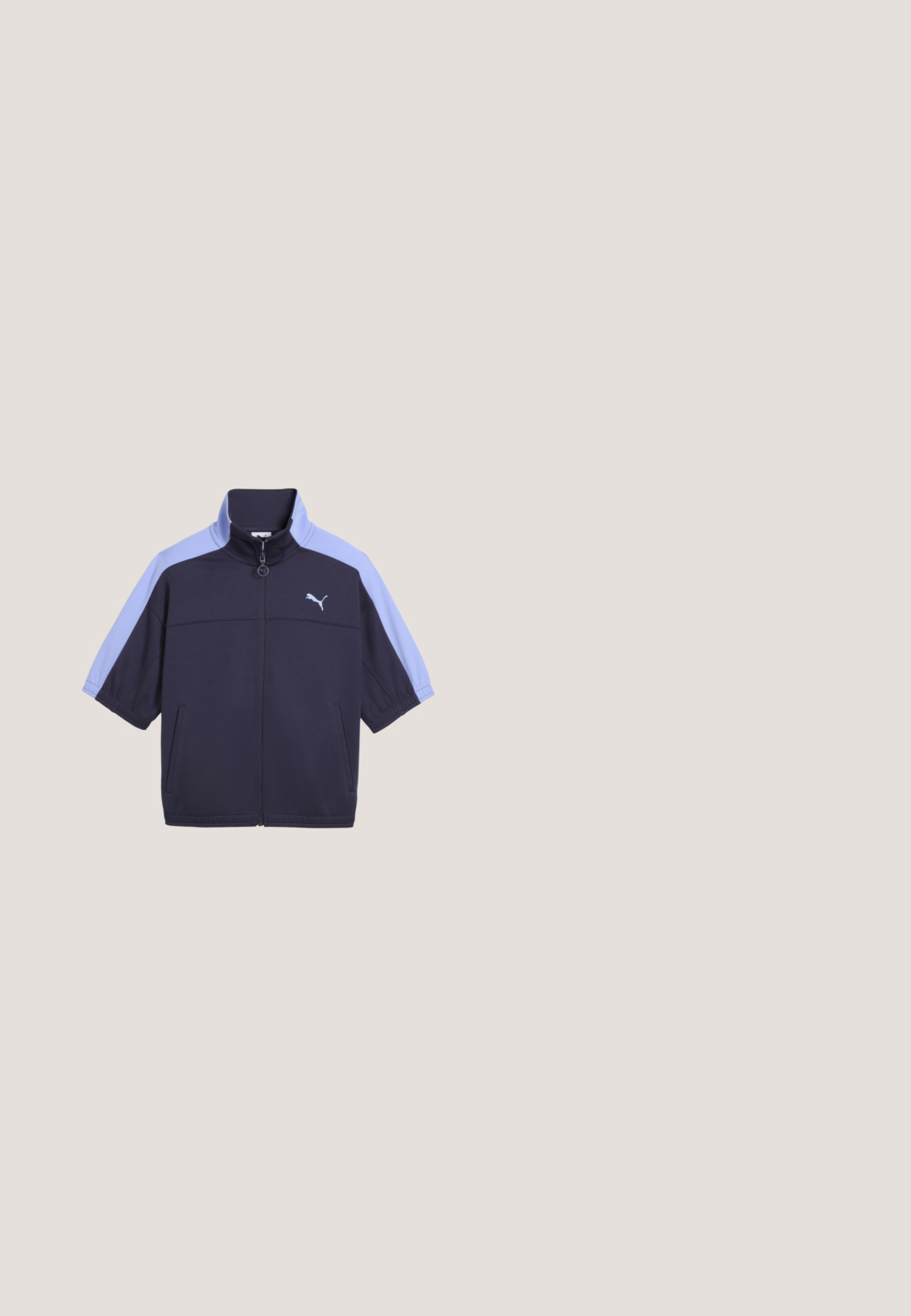Donkerblauw jack met lichtblauwe korte mouwen en hoge kraag, voorzien van een volledige ritssluiting aan de voorkant en een wit Puma-logo op de borst. Twee zijzakken.; Lichtblauw T-shirt met korte mouwen van zacht katoen, met een vierkante logopatch op de linkerborst en een klassieke ronde hals.; Marineblauwe sportbroek met elastische tailleband, zijzakken en klein wit Puma-logo op de bovenste linker dij.; Lichtgrijze sneaker met witte zijstreep en gumzool, zwevend gepositioneerd boven een betonnen oppervlak met wazige trappen op de achtergrond.; Lichtblauwe denim clutch met een zilveren rits en kleine bruine stiksel details op de onderste hoeken.; Draaide zilveren oorbellen met een gepolijste afwerking. Eén oorbel heeft een spiraalontwerp; de andere heeft een sluiting voor een veilige draagwijze.