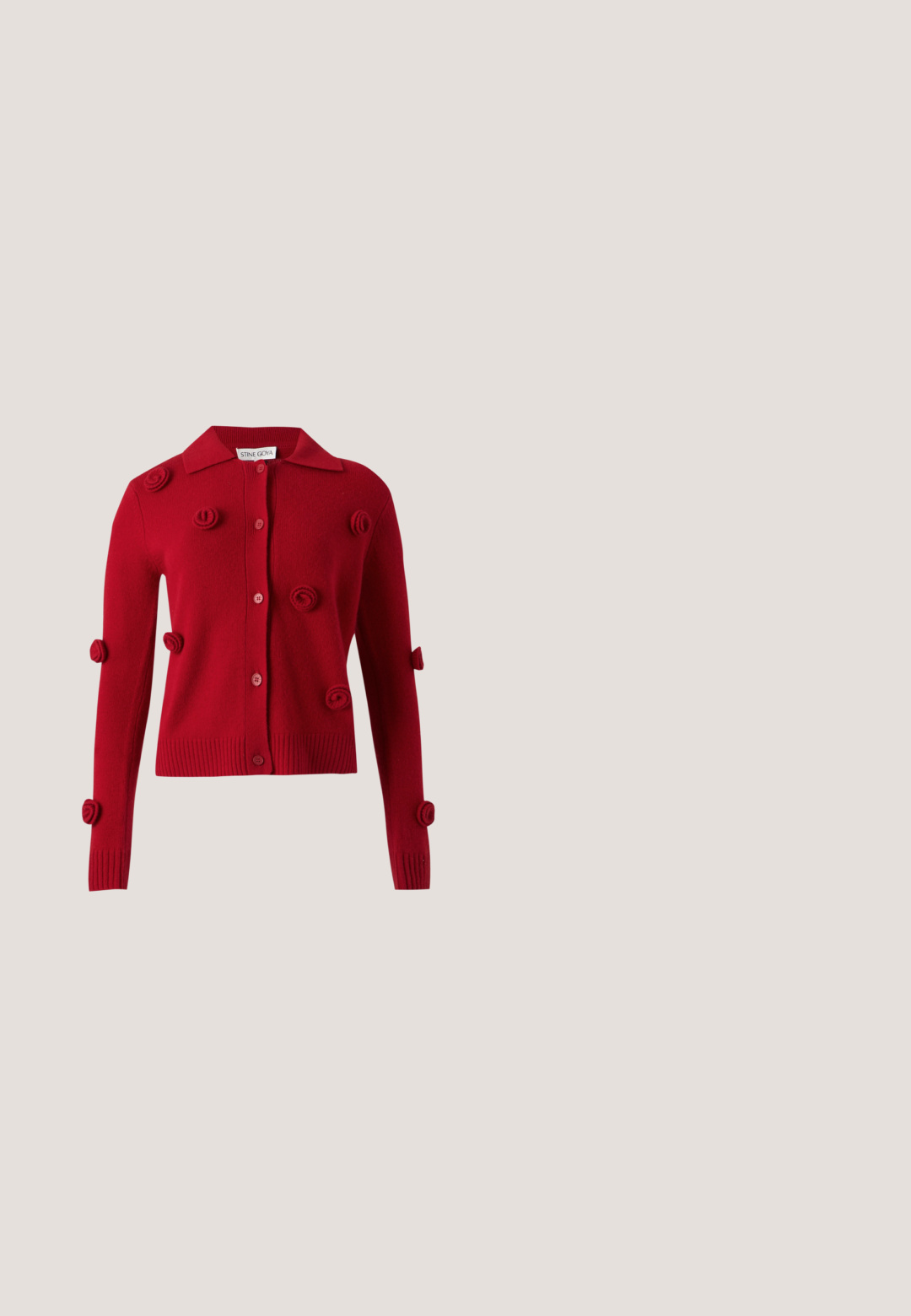 Cardigan rouge boutonné avec manches longues, orné d’embellissements en tissu texturé de forme circulaire dispersés sur le devant et les manches.; Haut gris à manches longues avec un col montant, fabriqué en tissu doux et texturé. Présente une coupe ajustée sans motifs ni accents visibles.; Pantalon large taille haute en lin gris clair avec plis devant et fermeture éclair dissimulée, présenté sur fond blanc.; Ballerine en cuir noir avec un bout arrondi, texture lisse et un accent logo doré sur le côté. Placée au-dessus d'une surface réfléchissante.; Sac à bandoulière en cuir noir avec sangle réglable, deux fermetures éclair verticales sur le devant et un petit emblème métallique en forme d'aile sous les fermetures éclair.; Boucles d'oreilles en argent en forme de créoles, ornées d'un cœur et d'un pendentif en forme de diamant. Texture lisse avec une finition polie.