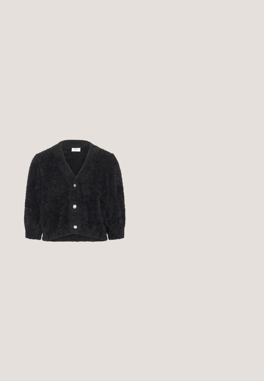 Cardigan noir en matière douce, avec un décolleté en V profond, des manches trois-quarts et cinq boutons décoratifs ressemblant à des gemmes.; Sac cabas en tissu noir avec des bretelles larges et arrondies et un compartiment principal ouvert, présenté sur fond blanc.; Pantalons larges en tissu noir texturé avec des fils blancs. Comprend des poches avant et une fermeture à bouton. Conception de taille plate.; Escarpin slingback en cuir noir à talon kitten, avec bout pointu et bride réglable avec boucle, sur fond blanc.; Sac à main en cuir noir brillant avec une forme structurée, deux poignées et une bandoulière réglable longue posée sur la base, sur fond blanc.; Anneau en argent lisse et poli avec un design moderne, incurvé et ouvert reposant sur une surface blanche.