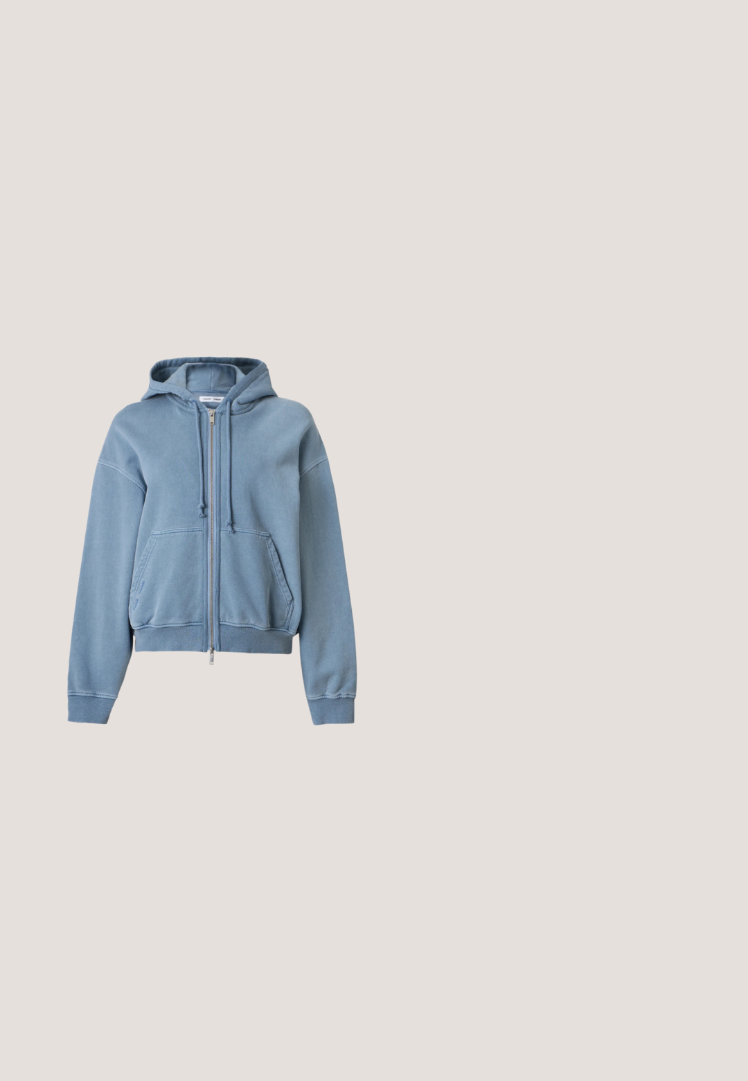 Sweat à capuche bleu zippé avec poches avant, capuche avec cordon de serrage et poignets et base côtelés, présenté sur un fond clair uni.; T-shirt bleu basique en coton avec un col rond, des manches courtes et un ourlet droit. Aucun motif ni accent visible.; Jean bleu clair à jambes larges avec une taille haute, bouton à l'avant, passants pour ceinture et une longue ceinture assortie en tissu.; Baskets de sport argentées avec une tige en synthétique lisse, semelle en caoutchouc et un design à lacets, assorties à des chaussettes blanches mi-mollet.; Sac fourre-tout en toile bleue avec doubles poignées supérieures, poches latérales, sangle d'épaule amovible et petite étiquette logo Calvin Klein à l'avant.; Paire de boucles d’oreilles créoles en métal argenté brillant, avec un motif de croissant superposé, sur fond blanc uni.