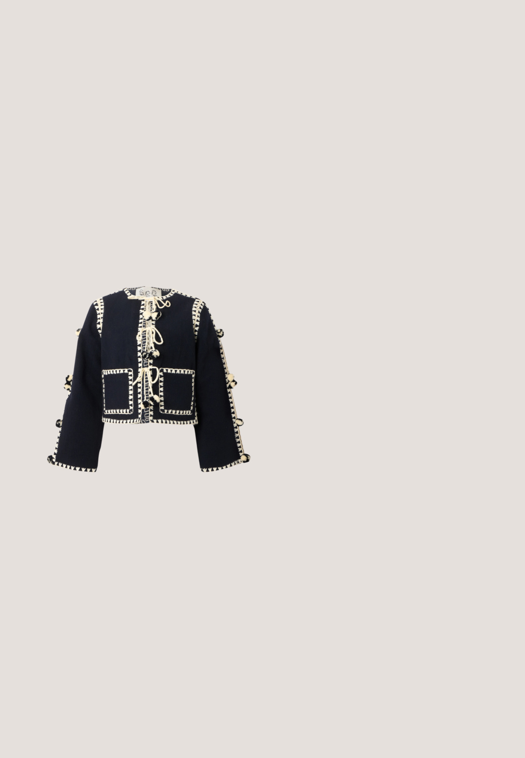 Chaqueta corta de manga larga negra con costuras decorativas en color crema, bolsillos frontales y lazos con pompones a lo largo del centro y las mangas.; Vestido maxi negro con tirantes finos, cuerpo ajustado y falda acampanada y fluida hecha de una tela suave. El dobladillo presenta una superposición transparente.; Mules negros de tacón con punta redondeada, hechos de cuero suave. Presentan una banda elástica y un tacón cilíndrico prominente.; Gafas de sol negras con un acabado brillante, lentes en forma ovalada y acentos del logo dorado DG en las varillas. Detalles laterales texturizados, diseño elegante.; Bolso de mimbre negro con forma de concha de vieira con parte superior curva y textura tejida sobre un fondo liso.; Collar de cordón negro ajustable con pequeñas cuentas amarillas y blancas y siete dijes de flores doradas espaciados uniformemente.