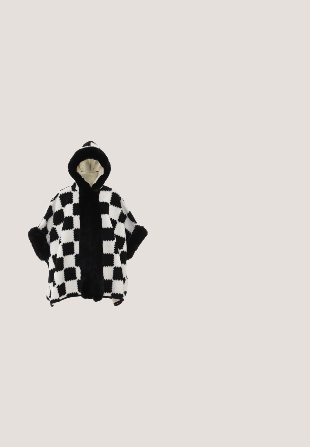 Sort og hvidternet hætteponcho med fake pelskant og manchetter. Blød tekstur, åbne ærmer og et varmt, hyggeligt design.; Sort fuzzy trøje med høj hals og bold hvide geometriske linjer, der danner rektangler og kurver over kroppen og ærmerne.; Sorte ribbede loungbukser med snoretræk i taljen og flare ben. Har et lille logo-accents i kontrasterende tråd.; Sort, fuzzy ankelstøvle med en struktureret overdel, der har en tykk sort gummisål og et mønster for greb og stabilitet.; Sort rektangulær håndtaske med blød pelsstruktur og en enkelt tynd læderrem på hvid baggrund.; Sølv snoede hængeøreringe med en glat finish, der har et markant spiraldesign og en blød tekstur.