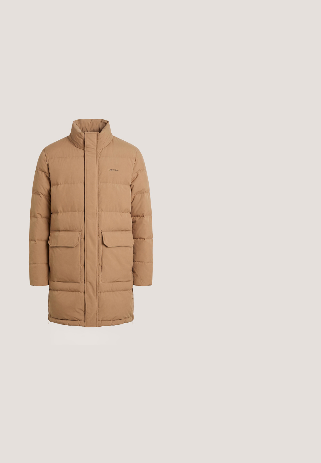 Abrigo largo de invierno acolchado en beige con cuello alto, cremallera frontal oculta, dos grandes bolsillos de solapa y logo de Calvin Klein en el pecho.; Sudadera con capucha de color crema con bolsillo frontal tipo canguro y pequeño logo rojo de CK en el pecho izquierdo.; Camiseta beige de manga corta con cuello redondo, con pequeño logo blanco "cK" en el pecho izquierdo y etiqueta Calvin Klein Jeans dentro del cuello.; Pantalones cargo beige con cintura y puños elásticos, cierre de botón, bolsillos laterales y bolsillos con solapa en ambos muslos. Pequeño logo en la solapa del bolsillo izquierdo.; Bota Chelsea de cuero negro flotando sobre un banco de madera con hierba verde al fondo.; Bolso bandolera de piel marrón oscuro Calvin Klein con dos compartimentos con cremallera y correa ajustable con cierres metálicos.