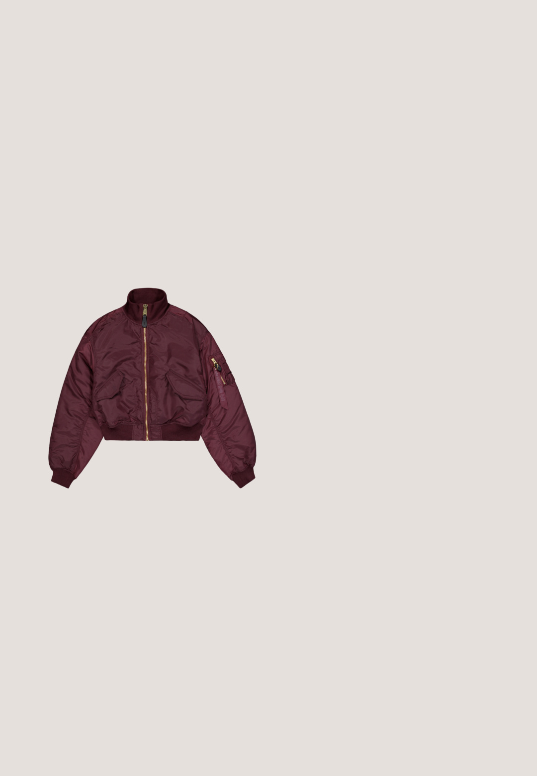 Bordeaux bomberjack met een hoge kraag, gouden rits, twee voorzakken en elastische manchetten. De stof heeft een gladde textuur.; Beige cropped t-shirt van katoen, met korte mouwen en een ronde halslijn. Het heeft een bordeauxrood 'Alpha Industries' logo op de achterkant.; Loszittende broek met elastische taille, voorzien van een camouflageprint met groene en bruine tropische bladeren.; Bruine suède sneaker met luipaardprintpanelen, zwart streepdetail en rubberen zool, zijaanzicht op neutrale achtergrond.; Donkerbruine handtas met een korte band en zilveren gespen, versierd met blauwe en witte veters aan elke kant, weergegeven tegen een witte achtergrond.; Zilveren oorringen met het woord "Perfect" gespeld in strass steentjes binnenin elke ring, op een witte achtergrond.