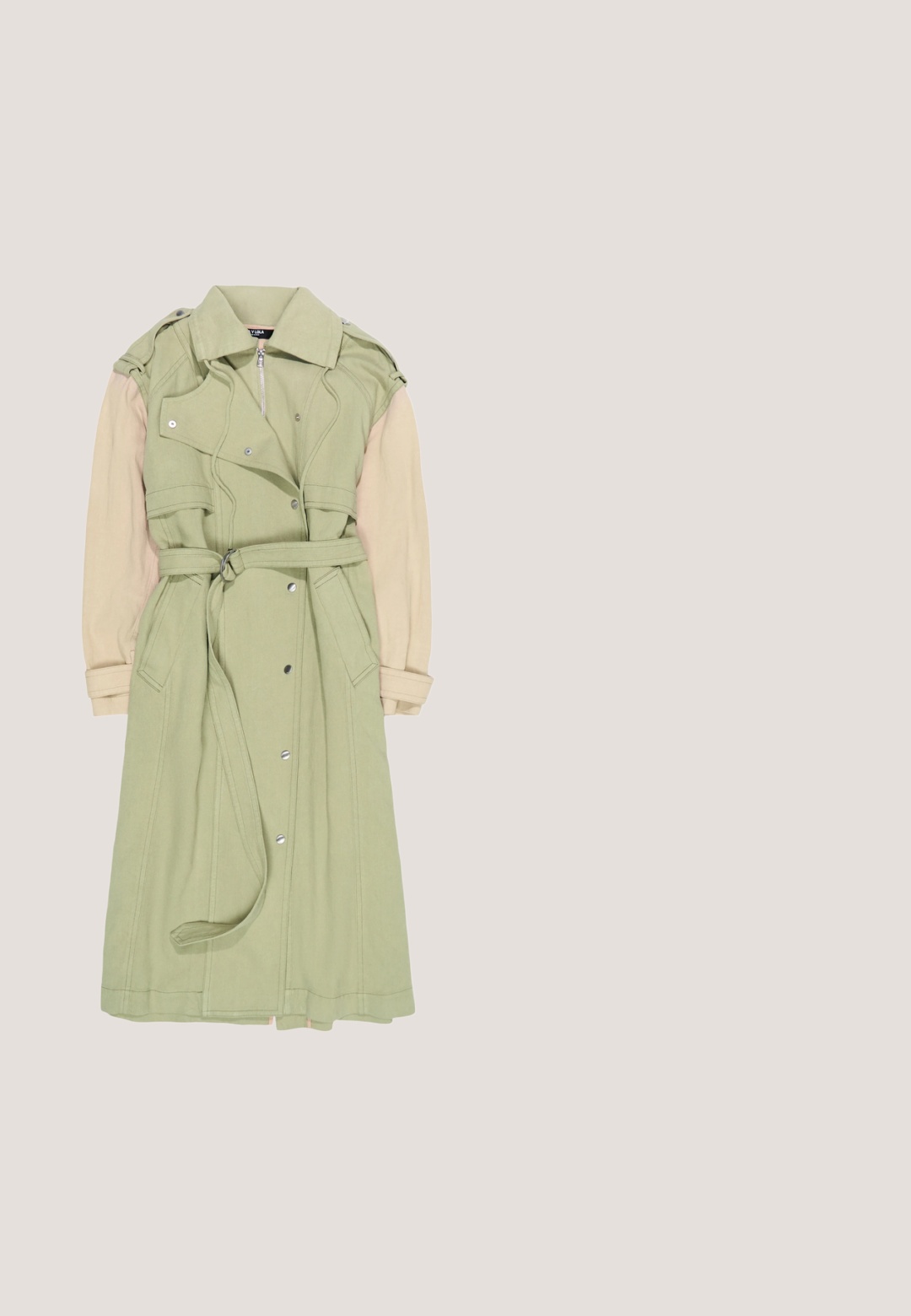 Hellgrüner Trenchcoat mit beigen Ärmeln, Knöpfen vorne, tailliertem Gürtel und Reißverschluss am Kragen mit Schulterklappen.; Olivgrüne Corduroy-Overalls mit weitem Bein, verstellbaren Trägern und einer strukturierten Oberfläche. Einfaches Design, keine sichtbaren Muster oder Beschläge.; Grüner Schlupfschuh mit dicker schwarzer Sohle, die ausgehöhlte Bereiche aufweist, glattem Obermaterial und kleinem ovalem Ausschnitt nahe der Ferse.; Grüne Sonnenbrille mit retro Katzenaugenform, transparentem Gestell, dunklen Gläsern und goldenen Beschlägen mit bunten Akzenten an den Bügeln.; Kleine Handtasche aus grünem und hellviolettem Stoff mit Blumenmuster, einem einzelnen Henkel und dem Schriftzug „marimekko“ auf der Vorderseite.; La Manso ICONIC - Ring - green