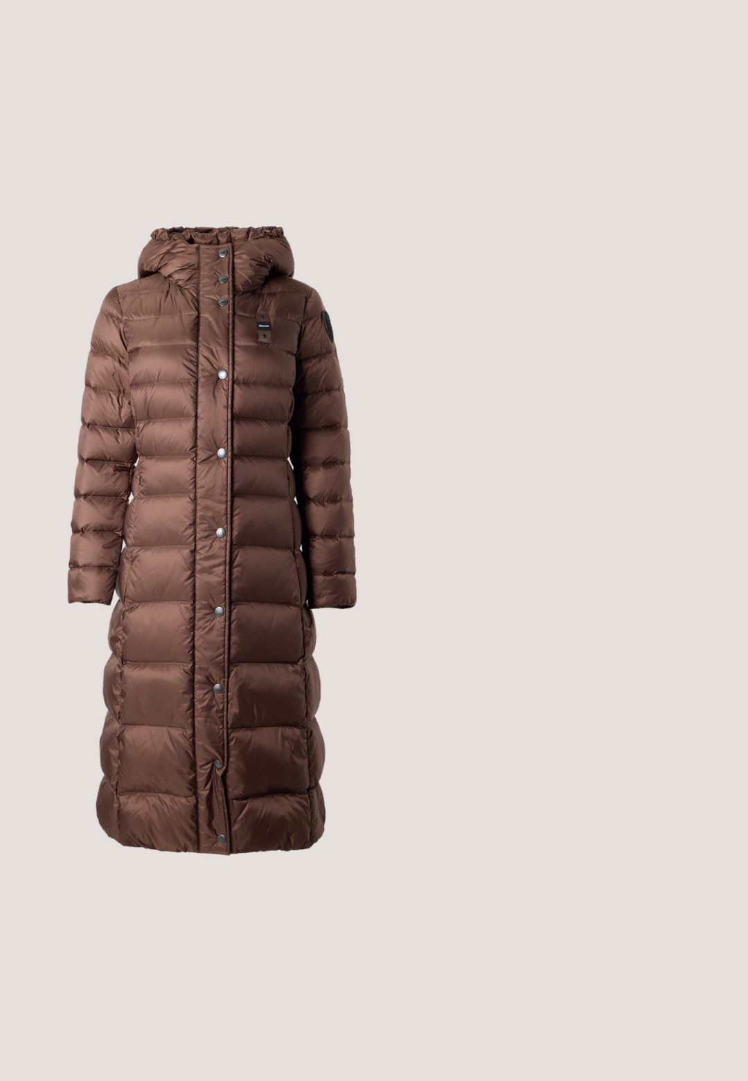 Lange bruine doorgestikte winterjas met capuchon, voorste drukknoopsluiting en zijzakken, weergegeven op een eenvoudige lichte achtergrond.; Bruin cropped T-shirt met korte mouwen en een ronde halslijn, met subtiel gedrukt EA7 Emporio Armani-logo op de borst en mouw, effen ontwerp.; Donkerblauwe denim jeans met een rechte pijp, vijf zakken, sluiting met bovenste knoop en oranje stiksels.; Bruine leren lage sneaker met veters aan de voorkant, gouden "Michael Kors"-logo, witte zool en gevlochten details bij de kraag.; Bruine leren schoudertas in halvemaanvorm met verstelbare riem en kleine zilveren logotekst onderaan in het midden.; Zilveren oorstuds met een glad, afgerond ontwerp, met een reflecterend oppervlak en zachte krommingen, wat een organische, kiezelachtige uitstraling geeft.