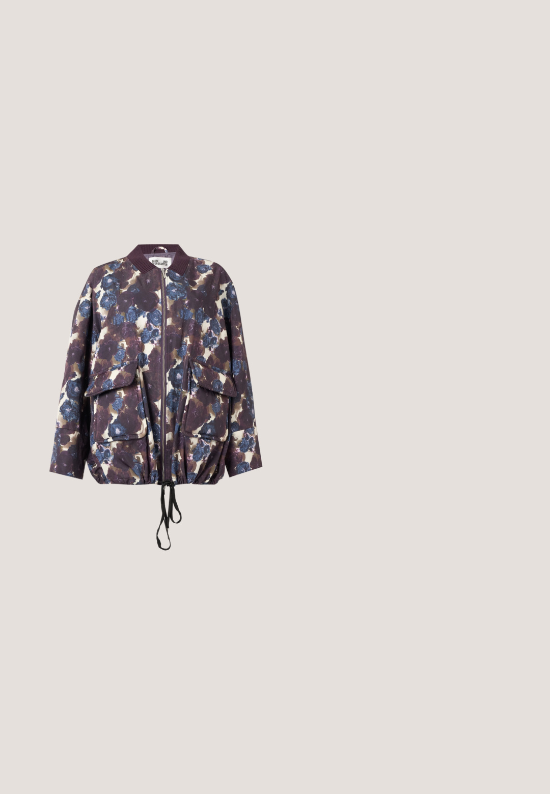 Bomberjacke mit Blumenmuster mit blauen und violetten Blumen, Frontreißverschluss, zwei großen Klappentaschen, geripptem Kragen und Tunnelzug am Saum.; Dunkelgrüner Hoodie mit Fronttasche, dekoriert mit Strassschrift, einem Totenkopf, einem Stern und Comic-Katzen-Grafiken.; Schwarze weit geschnittene Jeans mit grünen Akzenten, aus Jeansstoff, mit hoher Taille, vorderen Taschen und einem Metallknopfverschluss.; Leoprint Wildlederschuhe mit schwarzer, klobiger Sohle und Schnürsenkeln; ausgestattet mit Metallösen und strukturiertem Obermaterial für zusätzliche Details.; Dunkelgrüne Wildlederhandtasche mit zwei Griffen und passender abnehmbarer dunkler Leder-Reißverschlusstasche vor weißem Hintergrund.; Silberne Creolen, jeweils mit zwei kleinen befestigten Edelsteinen, einem hellgrünen und einem hellblauen, auf weißem Hintergrund dargestellt.