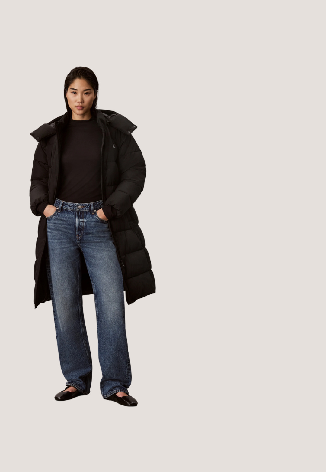 Vrouw met een lange zwarte donsjas, een zwarte top, blauwe wijde jeans en zwarte schoenen, staand met handen in de zakken.; Witte korte T-shirt met zwart Calvin Klein "cK" logo aan de voorkant en een trekkoord aan de zoom.; Marineblauwe leggings van rekbaar materiaal, met een gladde textuur en een elastische tailleband met het Calvin Klein-logo erop gedrukt.; Zwarte sportieve schoenen met een glad bovenwerk van synthetisch materiaal, een witte, stevige zool, gestructureerde accenten en zwarte veters. Minimalistisch ontwerp, zonder zichtbare logo's.; Zwarte rechthoekige Calvin Klein crossbodytas van gestructureerd leer, met ritssluiting bovenaan en verstelbare schouderband tegen een witte achtergrond.; Zilveren oorringen met een geometrisch ontwerp van in elkaar grijpende rechthoekige schakels, gepolijste afwerking en een steker sluiting.