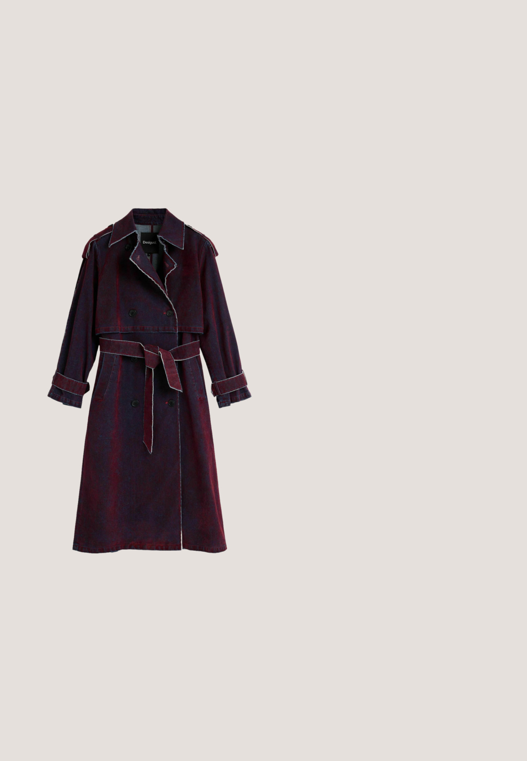 Lange donkerrode denim trenchcoat met dubbele rij knopen, brede revers, ceintuur in de taille en mouwen met manchetten, getoond op een witte achtergrond.; Het zwarte lange mouwjurk heeft levendige bloemen- en tekstprints, een gestructureerde stof en geplooide details aan één kant, wat zorgt voor een dynamische uitstraling.; Zwarte leren kniehoge laars met platte zool en een iets bredere bovenkant met een asymmetrische snit aan de buitenkant.; Zwarte ovale zonnebril met blauw getinte glazen en dikke pootjes, geplaatst op een witte ondergrond.; Zwarte leren handtas met gebogen vorm, gouden studs in verticale lijnen, geknoopte handgreep en verstelbare schouderriem met gesp.; Gouden ring met een rood-zwart geëmailleerd lieveheersbeestje ontwerp met zwarte stippen en afgeronde gouden accenten op een witte achtergrond.