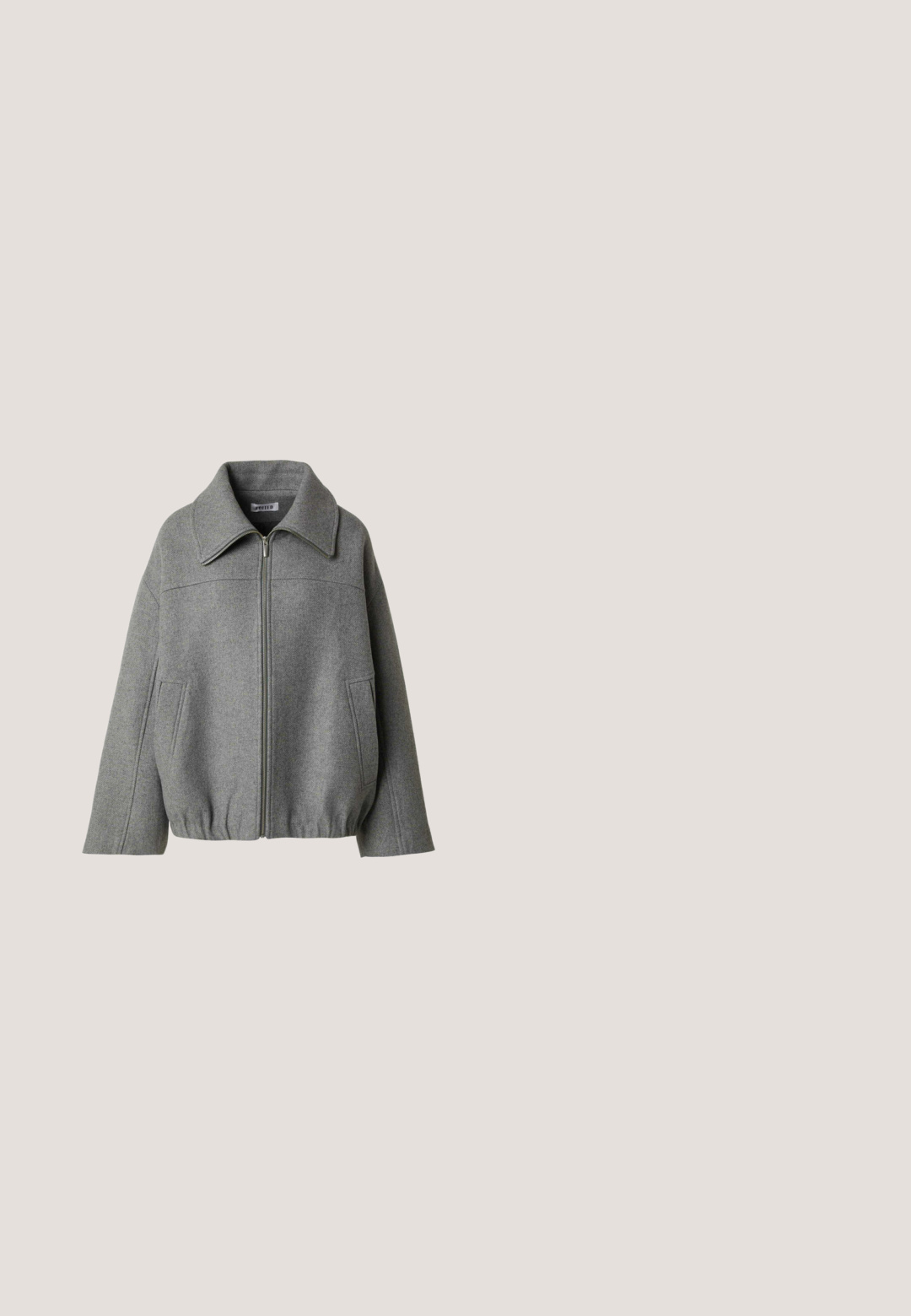 Grijze wollen jas met ritssluiting, brede kraag, lange mouwen, voorzakken en elastische zoom voor een ontspannen pasvorm.; Afgekorte grijze hoodie gemaakt van zachte stof, met een voorrits, twee zijzakken en een tunnelkraag met geribbelde manchetten.; Geknipt grijs T-shirt van katoen met een ronde halslijn, korte mouwen en een witte hoefijzerafbeelding in het midden.; Lichtgrijze joggingbroek met elastische boorden en tailleband, trekkoortje en rode en zwarte tekstgrafieken op het linkerbeen en de rechterkuit.; Zwarte sportschoen met een geprofileerde bovenkant van mesh, zilveren accenten, ondersteuning voor de voetenboog en een gevoerde zool met een duidelijk gesegmenteerd ontwerp.; Zwarte lederen handtas met gevlochten handvatten, ritsvak en hangende franjes. Gelaagde oppervlakte met metalen studs en hardwareaccenten.