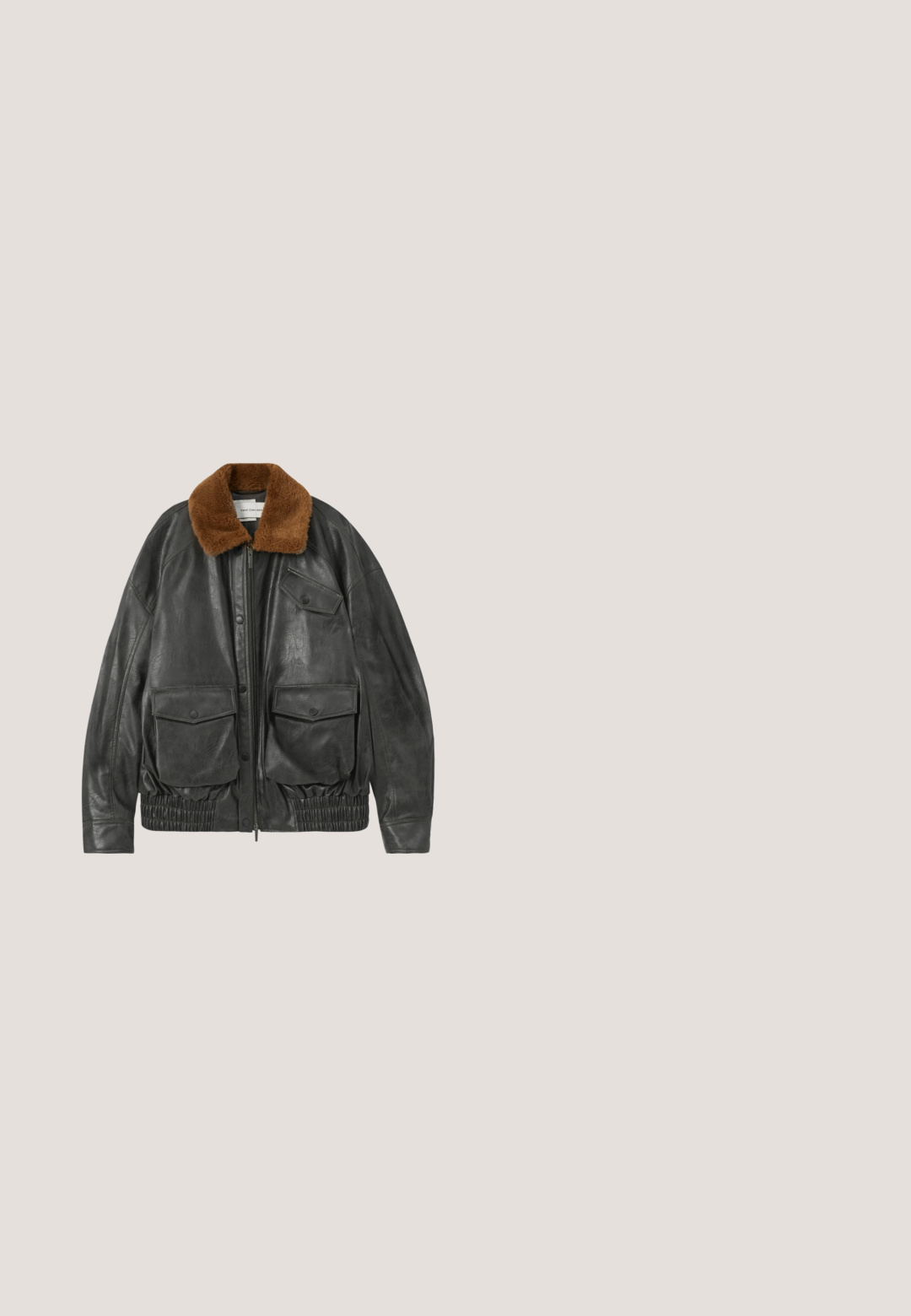 Veste en cuir noir avec un col en fausse fourrure marron, fermeture éclair, ourlet élastiqué et deux poches plaquées à l'avant. Texture lisse et coupe décontractée.; Pull vert foncé avec un graphisme de serpent enroulé autour d'un crâne et le mot « Voltaire » au-dessus du dessin.; T-shirt noir à manches courtes avec col rond, motif abstrait gris foncé subtil et tissu texturé, présenté à plat sur un fond clair.; Pantalon gris foncé à jambes larges avec poches avant, fermeture par bouton et coutures visibles sur toute la surface.; Botte de cowboy en cuir noir avec un bout pointu, une tige haute, des coutures décoratives et une quincaillerie en argent sur la sangle. Fini texturé.; Sac fourre-tout en toile grise avec deux anses et une poche avant ornée d'un motif de tête de loup cousu.