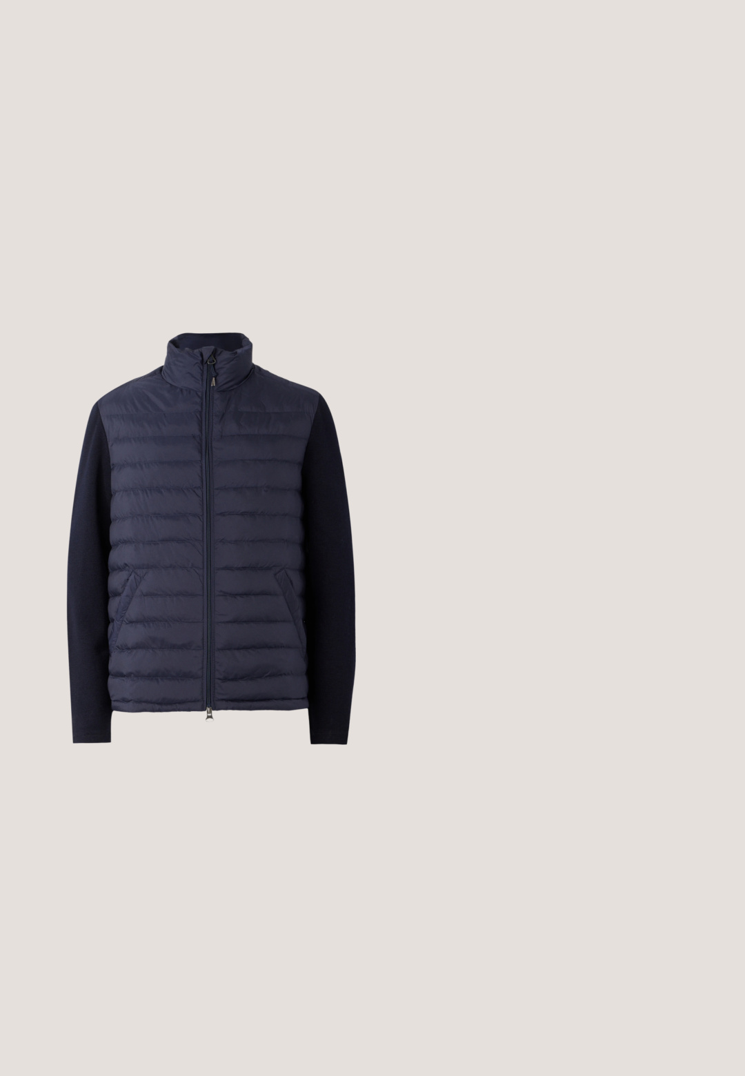 Marine pufferjack met een hoge kraag, ritssluiting aan de voorkant en een met padding gevuld lichaam. Gebreide mouwen en zijzakken zorgen voor een textuurcontrast.; Marineblauwe poloshirt met lange mouwen met een kraag met twee knopen, groene en witte gestreepte accenten op de kraag en manchetten, met een geborduurd logo.; Marineblauwe, vlakke broek van katoenmixstof, met een klassieke pasvorm en rechte pijpen. Heeft voorzakken en een knoopsluiting.; Zwarte suède loafer met gestikte details en een klein vlaggetje, tentoongesteld bovenop een beige tapijt met amberen transparante meubels op de achtergrond.; Donkerblauwe rechthoekige zonnebril met grijze lenzen, voorzien van rode accenten en een klein merklogo op de pootjes.; Tote bag van wit canvas met marineblauwe accenten. Voorzien van twee stevige handvaten en een logo patch op de voorkant. Rechthoekige vorm.