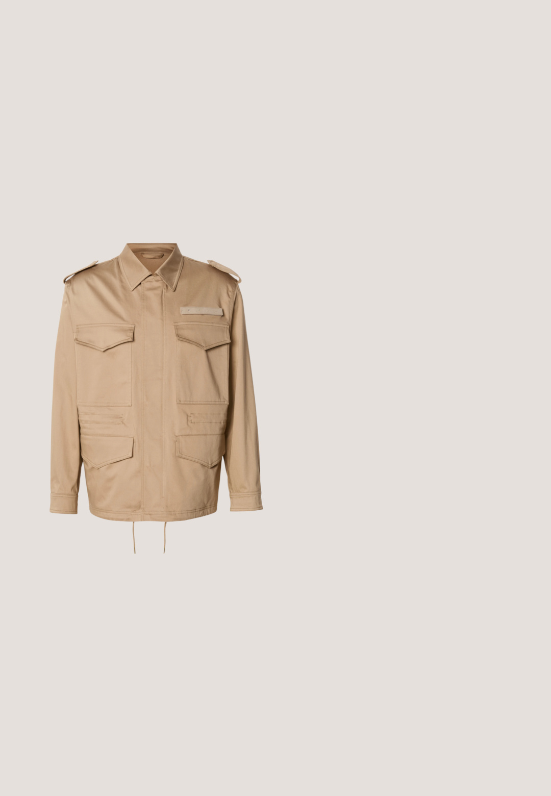Beige werkjack met twee borstzakken en twee lagere zakken. Heeft een kraag en knopen op de schouderbanden. Verstelbaar trekkoord aan de zoom.; Bruine gebreide trui met een ronde hals, geribbelde manchetten en zoom, en een klein blauw "HUGO"-logo op de borst. Overal een gladde textuur.; Navyblauwe, langarmpoloshirt van linnen, met een bandkraag, knopenstrip en een zachte textuur zonder patronen of versieringen.; Donkerblauwe cargobroek met rechte pijpen, twee zijzakken en een vlakke voorkant. Gemaakt van een lichtgewicht stof.; Bruine suède Chelsea-laars met zwart elastisch zijpaneel, zwarte zool en treklus aan de achterkant, zijaanzicht.; Lichtbruine leren riem opgerold met een glanzende zilveren rechthoekige metalen gesp op een witte achtergrond.