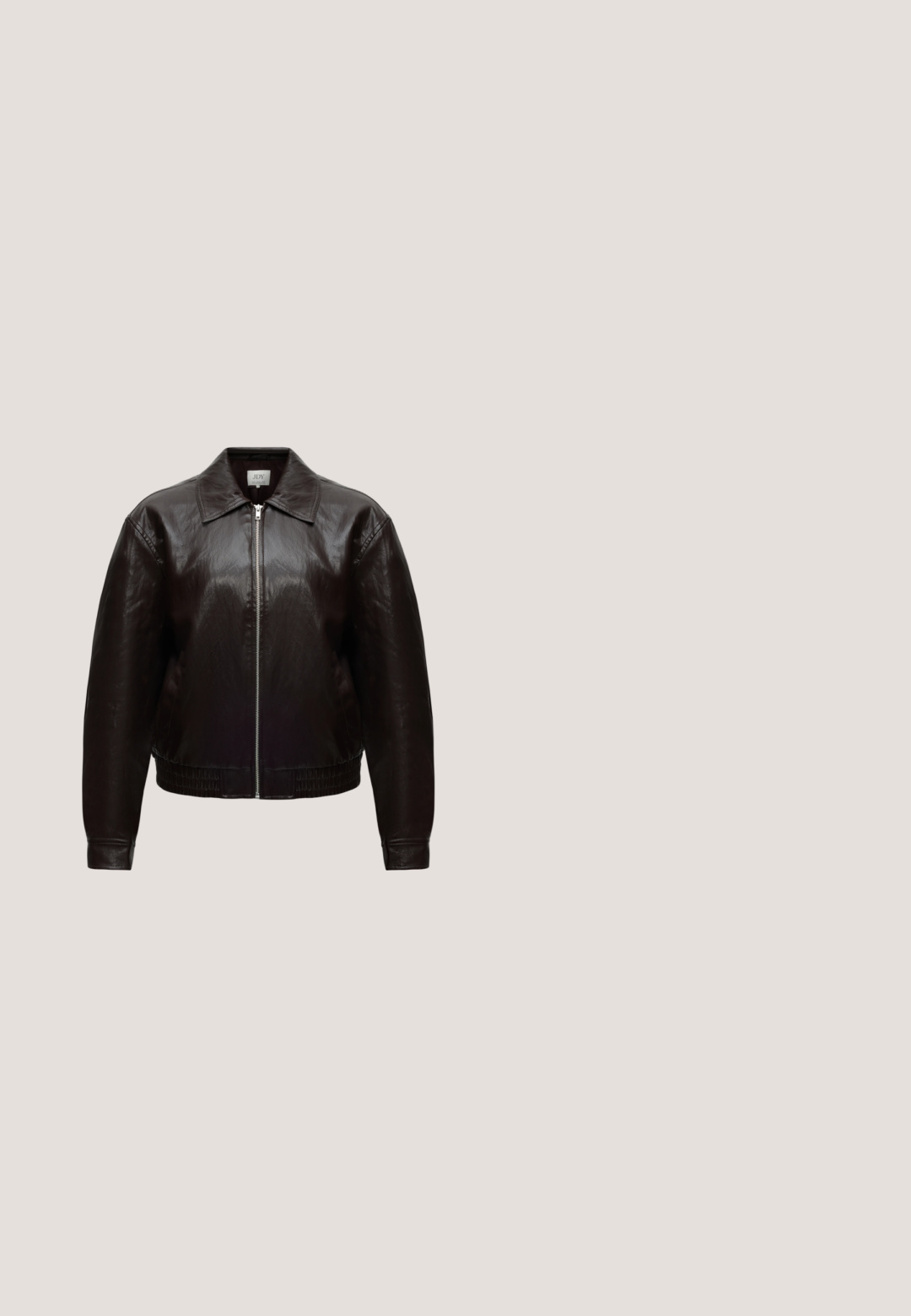 Chaqueta de cuero negro con cremallera frontal, cuello puntiagudo, mangas largas y dobladillo elástico sobre un fondo claro y liso.; Camiseta de algodón marrón con cuello redondo clásico, mangas cortas y un dobladillo recto. Textura suave, sin estampados ni adornos.; Pantalones anchos marrones con cintura elástica y cordón, mostrados sobre un fondo blanco liso. Sin logotipos ni estampados visibles.; Botín de piel marrón con un diseño elegante, puntera afilada y tacón cuadrado. Textura suave y silueta minimalista.; Bolso de hombro de cuero marrón oscuro brillante con una sola correa ancha y detalle de hebilla en un lado, colocado sobre un fondo claro y sencillo.; Collar tono oro con tres colgantes irregulares, lisos y con forma de guijarro, en una cadena delgada con cierre ajustable.