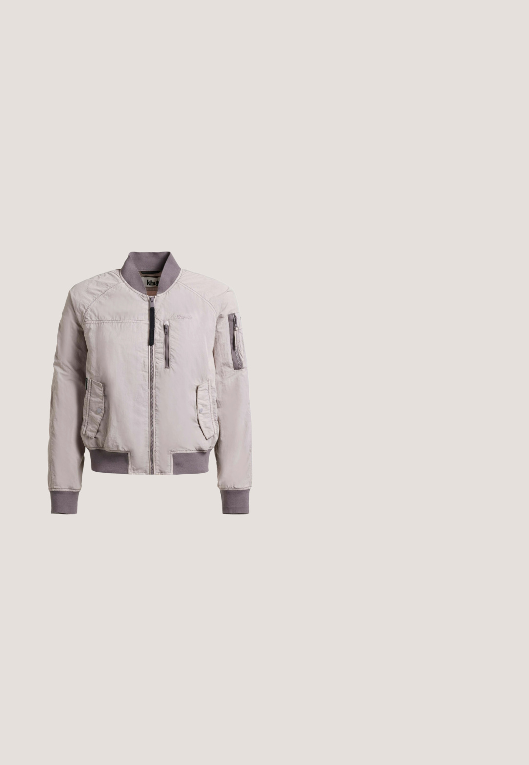 Chaqueta bomber gris clara con cuello, puños y bajo acanalados, con bolsillos en el pecho y brazos con cremallera, y bolsillos laterales con botones a presión.; Tela blanca con un estampado floral y abstracto en rosa, azul y naranja. Presenta el texto "AMALFI BATHER" en negro en la parte inferior.; Pantalones de tirantes de pana marrón con piernas anchas, tirantes ajustables y bolsillo frontal. Textura suave con patrón de acanalado vertical.; Zapatilla baja de ante rosa pastel con cordones blancos, suela de goma blanca, detalle de franja lateral y tirador en el talón.; Bolso tote color crema con patrón floral y pequeños personajes de dibujos animados con vestidos, con los logotipos de Cath Kidston y tokidoki.; Collar de oro con una cadena delicada, conector ovalado y un pequeño colgante en forma de corazón con superficie brillante, que presenta un diseño sencillo pero elegante.