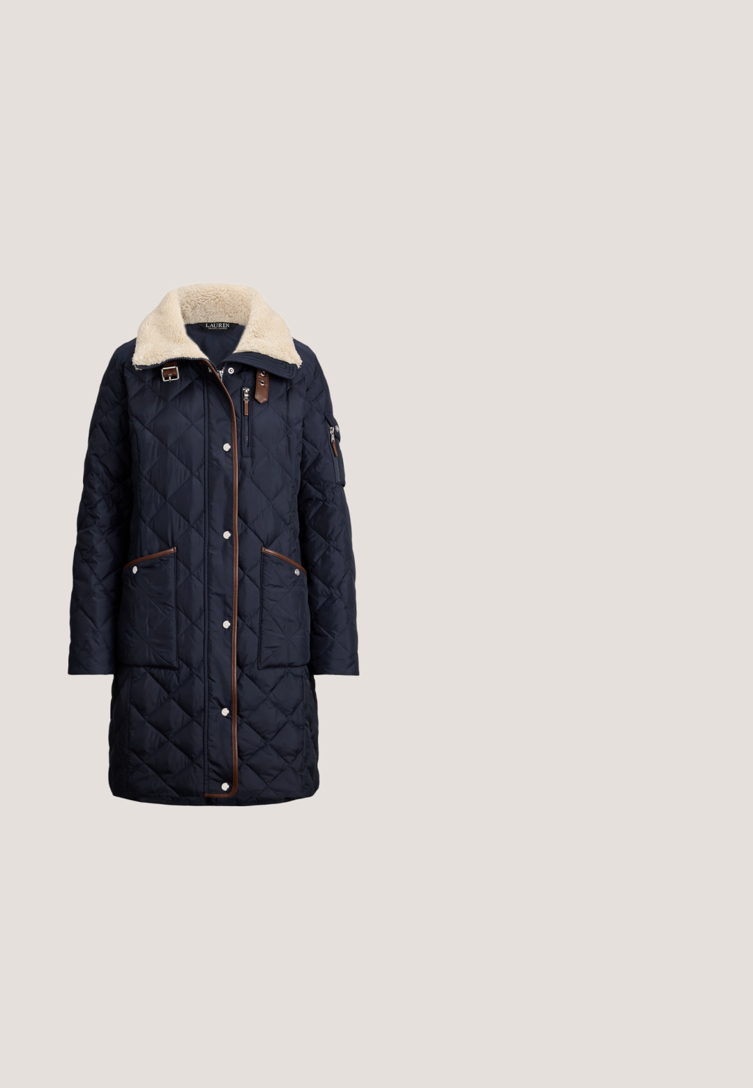 Marineblå quiltet pufferjakke med krave i creme-faux skind, brune accenter, store lommer og sølvfarvede trykknapper. Har en sidelommer med lynlås.; Kremfarvet kabelstrikket langærmet sweater med ribstrikkede manchetter og kant, med en lille broderet logo på venstre bryst.; Lyserød langærmet skjorte med knapkrave, hvide knapper og lille broderet logo på venstre bryst. Blødt bommateriale.; Højtaljede blå jeans i denim med klokkeformede ben og let falmet område foran på låret, vist mod hvid baggrund.; Sort tekstureret læderloafer med lav hæl og klassisk penny-stropdetalje, vist i profil mod en ensfarvet lys baggrund.; Marineblå skuldertaske i tekstureret læder med en enkelt rem, sølvringdetalje og lille rødt logo nær bunden i midten.