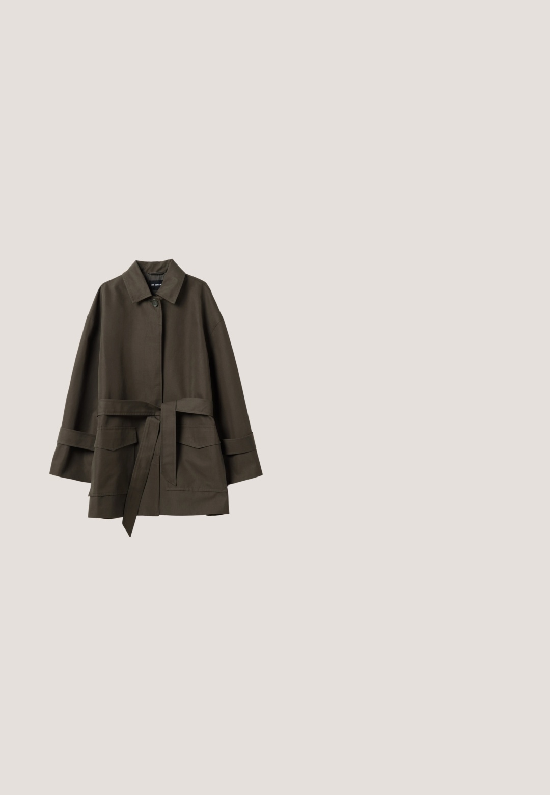 Donkergroene olijfgroene jas met riem, brede mouwen, knopen aan de voorkant en twee grote klepzakken.; Olijfgroene V-hals blouse van gestructureerde stof, met drie knopen aan de voorkant en driekwart mouwen met brede manchetten.; Olijfgroene casual broek met elastische tailleband, voorzakken met klep en opgerolde pijpen, plat gelegd op een witte achtergrond.; Bruine suède loafer met franjes zwevend boven een gestructureerd beige tapijt en een bijpassende beige bank op de achtergrond.; Zachte olijfgroene suede tote bag met twee schouderbanden en een eenvoudige knoopsluiting op een witte achtergrond.; Bruine leren halsketting met een verstelbaar koord en een gouden druppelhanger. Het ontwerp heeft eenvoudige, strakke lijnen en een gladde textuur.