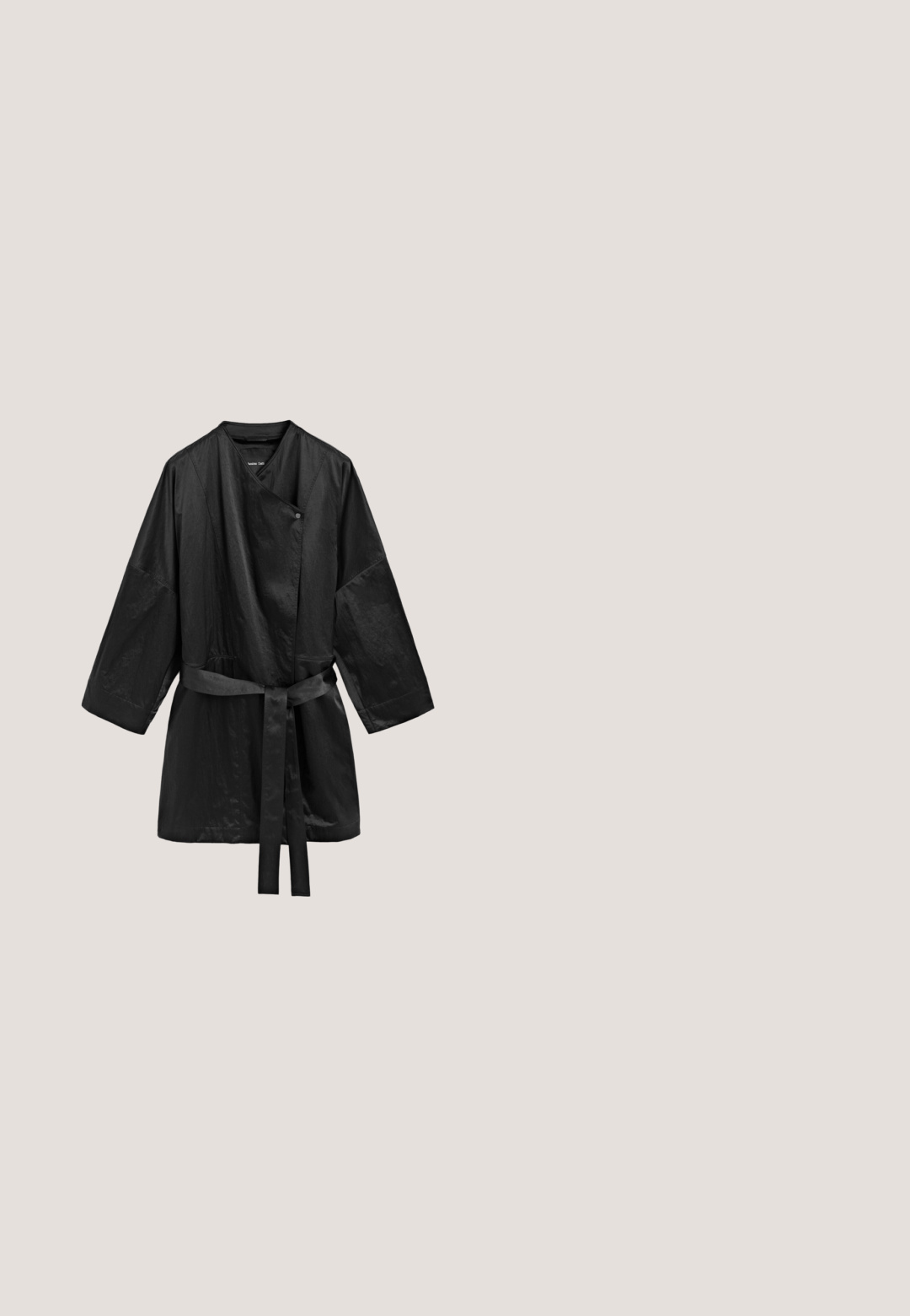Black long-sleeve wrap jacket with a waist belt and single snap button closure, made of slightly shiny fabric, displayed on white background.; Black short-sleeve romper with collar, front buttons, and a tied waist belt, made from lightweight fabric.; Black rubber flip-flop with textured footbed and smooth Y-shaped strap on a plain light background.; Black cat-eye sunglasses with dark lenses. Made of glossy plastic, featuring a subtle gold accent on the temple. Smooth texture and bold shape.; Black tote bag featuring large white text patterns. The bag has two handles and a sturdy, textured fabric construction.; Stretch bracelet with alternating black cylindrical and small gold curved beads on a white background.