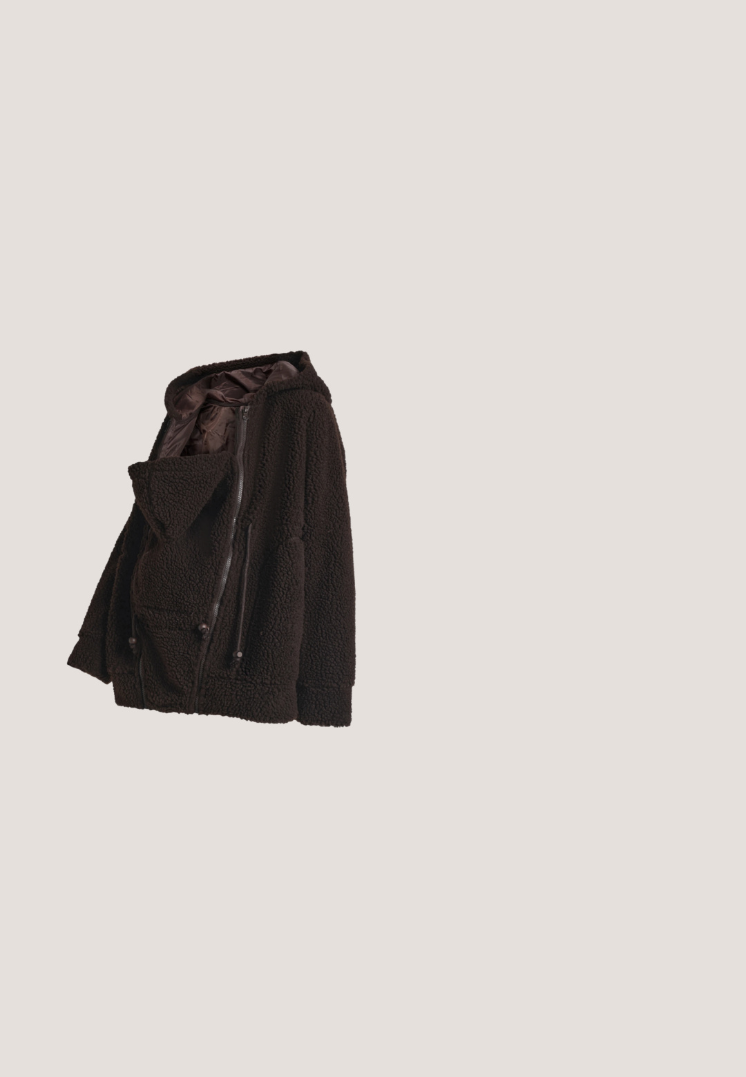Donkerbruine fleecejas met capuchon van zachte, gestructureerde stof, met ritssluiting aan de voorkant en trekkoorden, plat neergelegd op een witte achtergrond.; Zwart geribd zwangerschaps-T-shirt met korte mouwen en ronde hals, ontworpen om over een zwangere buik te passen.; Zwarte zwangerschapsjeans met een rekbare tailleband over de buik, slim fit en voorzakken met een gladde textuur.; Zwarte leren enkellaars met lage blokhak en zijrits op een effen lichtgrijze achtergrond.; Donkerbruine leren en suède handtas met korte handvatten, een afneembare schouderriem en een klein hangend leren label.; Gouden creolen met een gladde afwerking, voorzien van een hangende transparante ovale hanger. Simpel ontwerp met de nadruk op elegante vormen.