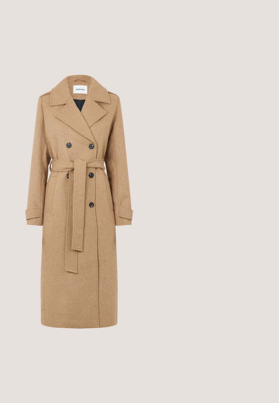 Manteau en laine couleur camel à double boutonnage, avec de grands revers et une ceinture à nouer. Présente deux poches avant et des boutons foncés.; Blouse blanche à manches longues en tissu léger avec col haut et un grand nœud au niveau du cou, dotée d'une fermeture à boutons sur le devant.; Pantalons bleu marine en tissu lisse et texturé. Présentent une coupe droite avec une taille simple et des coutures latérales.; Chaussure noire en cuir à talons hauts avec un bout pointu et une silhouette élégante, dotée d'un talon bas et d'un intérieur doux.; Sac cabas en cuir noir avec double poignée et plaque logo dorée, accompagné d'une petite pochette à motif géométrique en noir, blanc et beige.; Boucles d'oreilles rondes en ton doré, mettant en avant une large perle blanche lisse au centre, entourée d'un serti en or poli.