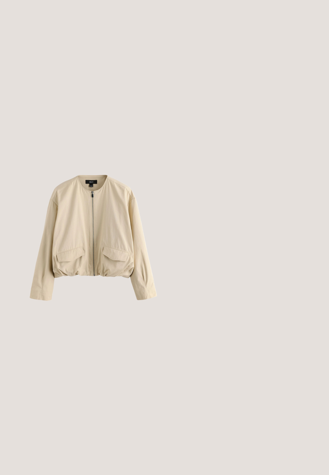 Beige rits-top met een ronde halslijn, voorzien van een metallic ritsdetail aan de voorkant en een gladde, zacht aanvoelende stof.; Crème gebreide trui met een losse pasvorm, korte mouwen, geribbelde zoom en een textuurpatroon, gemaakt van zacht, comfortabel materiaal.; Beige gebreide mouwloze trui met diepe V-hals, plat liggend op een witte achtergrond.; Beige wijde broek met elastische tailleband en zijzakken, gemaakt van soepele, lichte stof.; Beige suède instapschoen met afgeronde neus, lage platte hak, doorgenaaide zool en elastische zij inzet voor gemakkelijk aan- en uittrekken.; Grote, zachte beige suède hobo tas met een brede schouderband en een nonchalante, ongestructureerde vorm, tegen een witte achtergrond.