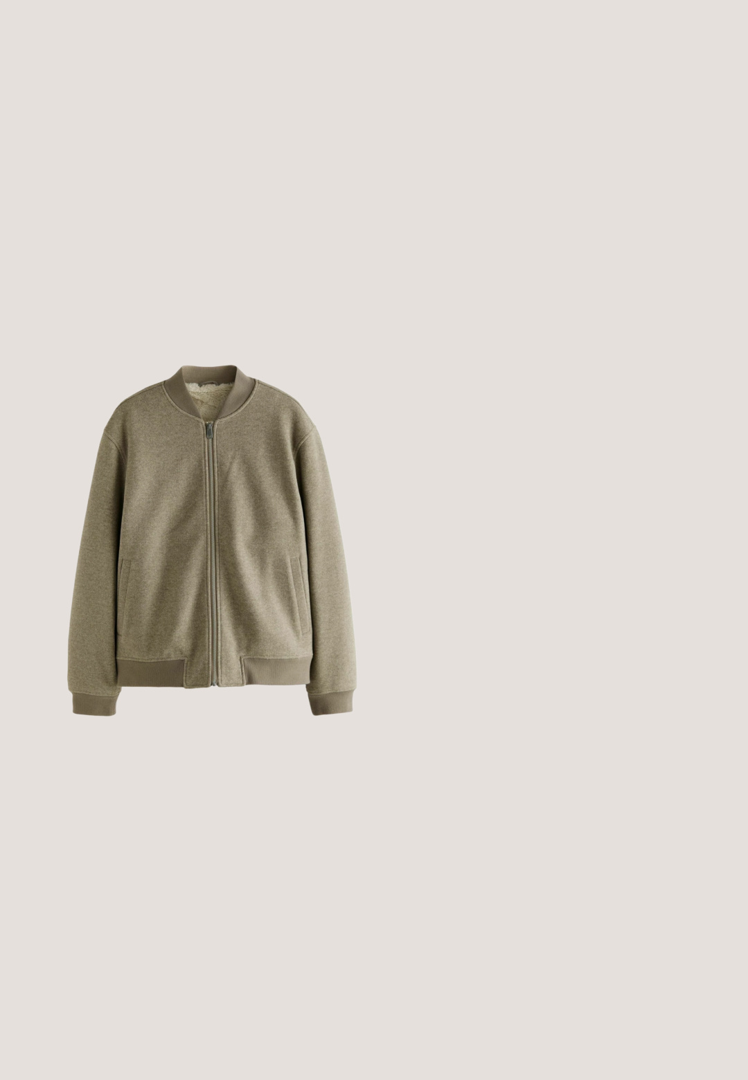 Chaqueta bomber verde oliva fabricada en tejido suave, con cierre de cremallera, puños acanalados y bolsillos laterales. El interior cuenta con un forro de felpa.; Suéter de punto acanalado beige con escote en V y mangas largas. Presenta un ajuste relajado y una tela texturizada para mayor calidez y comodidad.; Camiseta blanca lisa de manga corta y cuello redondo, mostrada sobre un fondo blanco, talla mediana, con etiquetas de ropa visibles dentro del cuello.; Pantalones gris claro de pierna recta con cintura elástica, cierre de botón y bolsillos laterales, mostrados planos sobre fondo blanco.; Zapatilla blanca de AllSaints con cordones, logo y texto en japonés suspendida sobre un suelo de hormigón pulido con bloques de vidrio esmerilado en el fondo.; Bolsa tote de lona color crema con bolsillo delantero, dos asas, correa de hombro ajustable y pequeño texto amarillo "O.N.S" en la parte inferior derecha del bolsillo.