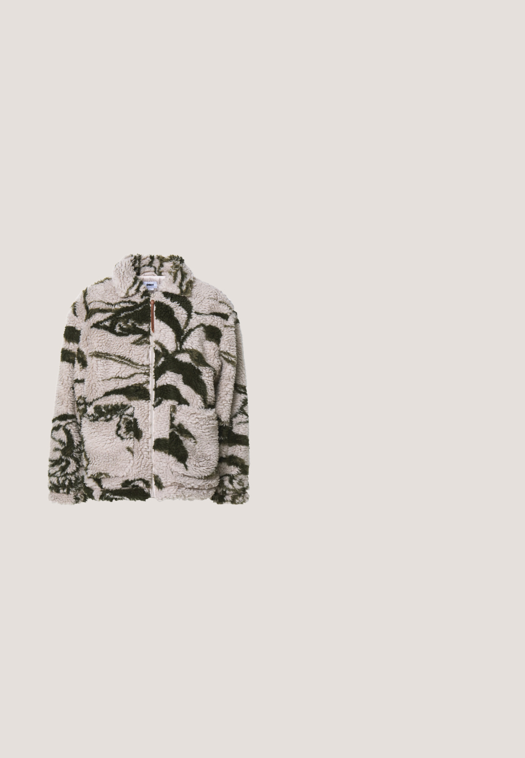 Fleece-tyynysatula beige-värissä, jossa on vihreitä kukkakuvioita, sisältää kaksi etutaskua, korkean kauluksen ja pehmeän, tekstuurisen kankaan.; Tummansininen neulepaita, jossa on teksturoitu kuvio, korkea kaulus ja ribbireunus. Valmistettu pehmeästä kankaasta, jossa on hieman löysä istuvuus.; Valkoinen pitkähihaisen t-paita, joka on valmistettu puuvillasta. Siinä on pieni kultainen logo rinnassa ja pyöreä pääntie. Yksinkertainen muotoilu ja normaali istuvuus.; Siniset farkut suoraa lahjetta, joissa on hieman haalistumista reisissä ja polvissa, viidellä taskulla ja napilla kiinnitettävä malli.; Kiiltävä ruskea nahkakenkä, jossa on paksu musta pohja ja ainutlaatuinen nauhoitus, sijaitsee beigen maton päällä lähellä pyöreitä oransseja huonekaluja.; Tummanvihreä kangaskassi leveillä kahvoilla, jossa valkoiset graafiset tekstit: "Maison Kitsuné", "Tokyo Paris" ja "Palais Royal" kukkaornamentteineen.