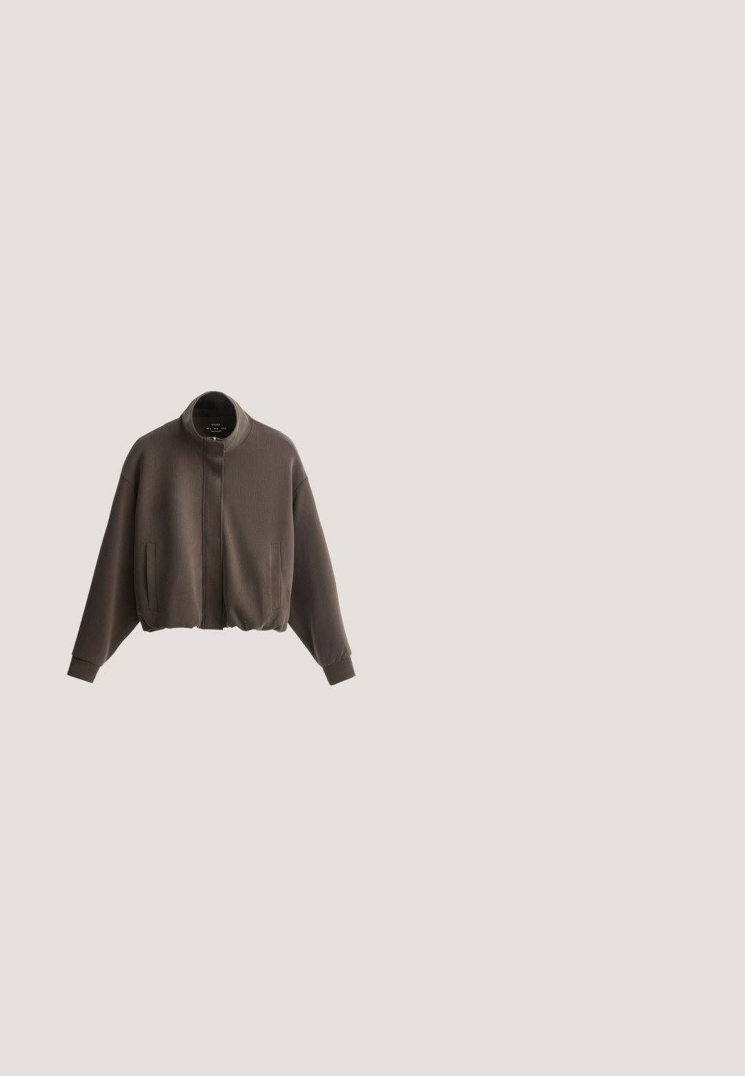 Veste bomber marron foncé côtelée avec poches avant, fermeture éclair et boutons-pression, et poignets et col côtelés, présentée sur fond blanc.; T-shirt uni marron foncé à manches courtes et col rond en tissu lisse avec une étiquette de marque visible au niveau de l'encolure.; Pantalon vert olive ample avec taille élastique et cordons au bas, présenté à plat sur fond blanc.; Botte haute en cuir marron foncé avec petit talon et détail de boucle sur la bride latérale, vue du côté extérieur sur fond blanc.; Lunettes de soleil avec verres foncés et monture œil-de-chat incurvée en motif écaille sur fond blanc.; Sac fourre-tout en daim marron foncé avec une base large et des bretelles fines en cuir, présenté sur fond blanc.