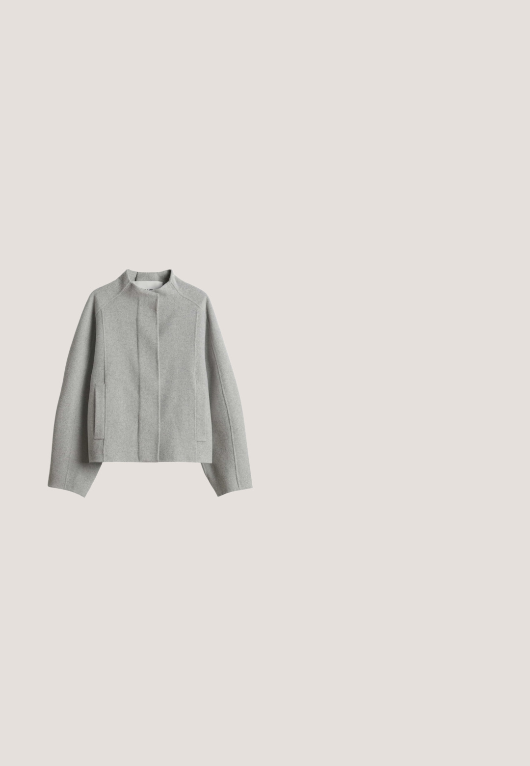 Hellgraue Wolljacke mit langen Ärmeln, Stehkragen, verdecktem Frontverschluss und zwei vertikalen Seitentaschen.; Kurzärmeliger grauer Strickcardigan mit Knöpfen, geripptem Kragen, Bündchen und Saum, flach auf einem weißen Hintergrund ausgelegt.; Weißes Kleidungsetikett mit Marke "minissimi", Größe "S" und dem Text "feel bamboo" auf glattem weißem Stoff.; Schwarze, weite Hosen aus einem weichen, strukturierten Stoff. Mit einem elastischen Bund und zwei Seitentaschen. Gefälteter Vorderdesign.; Schwarzer flacher Loafer aus Leder mit niedrigem Absatz und dekorativer Schleife auf dem Vorderblatt, von der Seite auf weißem Hintergrund gesehen.; Schwarze Lederhandtasche mit strukturiertem Oberflächen, zwei oberen Griffen, abnehmbarem Schultergurt und goldfarbener Branding auf der Vorderseite.