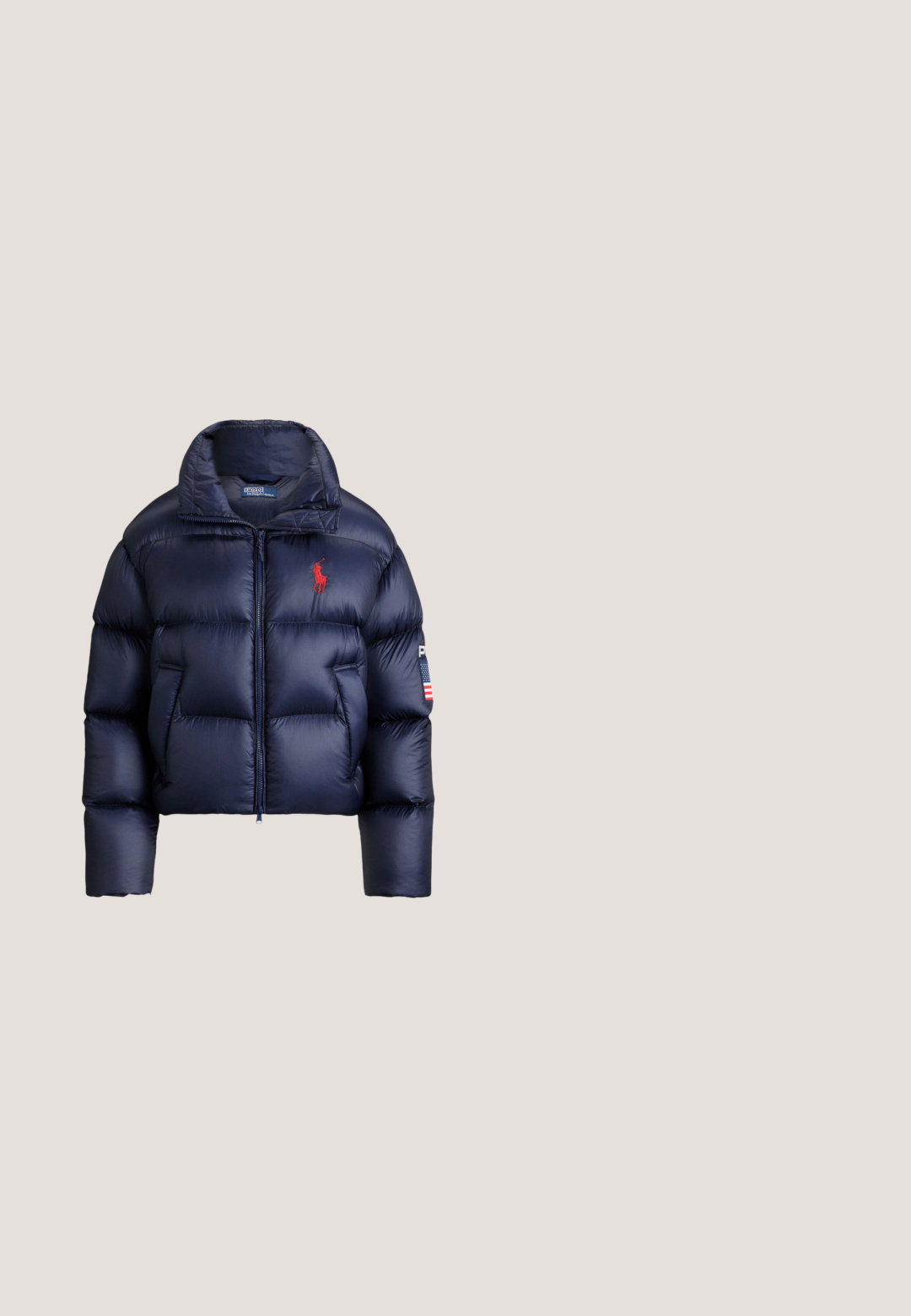 Marineblå dunjakke med høj krave, lynlås foran, rødt broderet logo og hvide og blå detaljer på ærmet.; Blå strikket sweater med kabelmønster og et strikket amerikansk flagdesign. Ribstrikket rund hals og kant. Brandlogo syet nederst.; Hvid kortærmet t-shirt med rund halsudskæring og et lille mørkt broderet logo nær den nederste kant på en ensfarvet baggrund.; Navyblå bukser med vide ben lavet af bomuld, med knaplukning foran, bæltestropper og en glat, tekstureret overflade.; Hvid sneaker med blå og navy accenter, ruskindssnude, snøredesign og tekstureret sål for greb.; Lyseblå mulepose med to tynde håndtag, guld lynlås og lille gyldent logo centreret foran mod en ensfarvet baggrund.