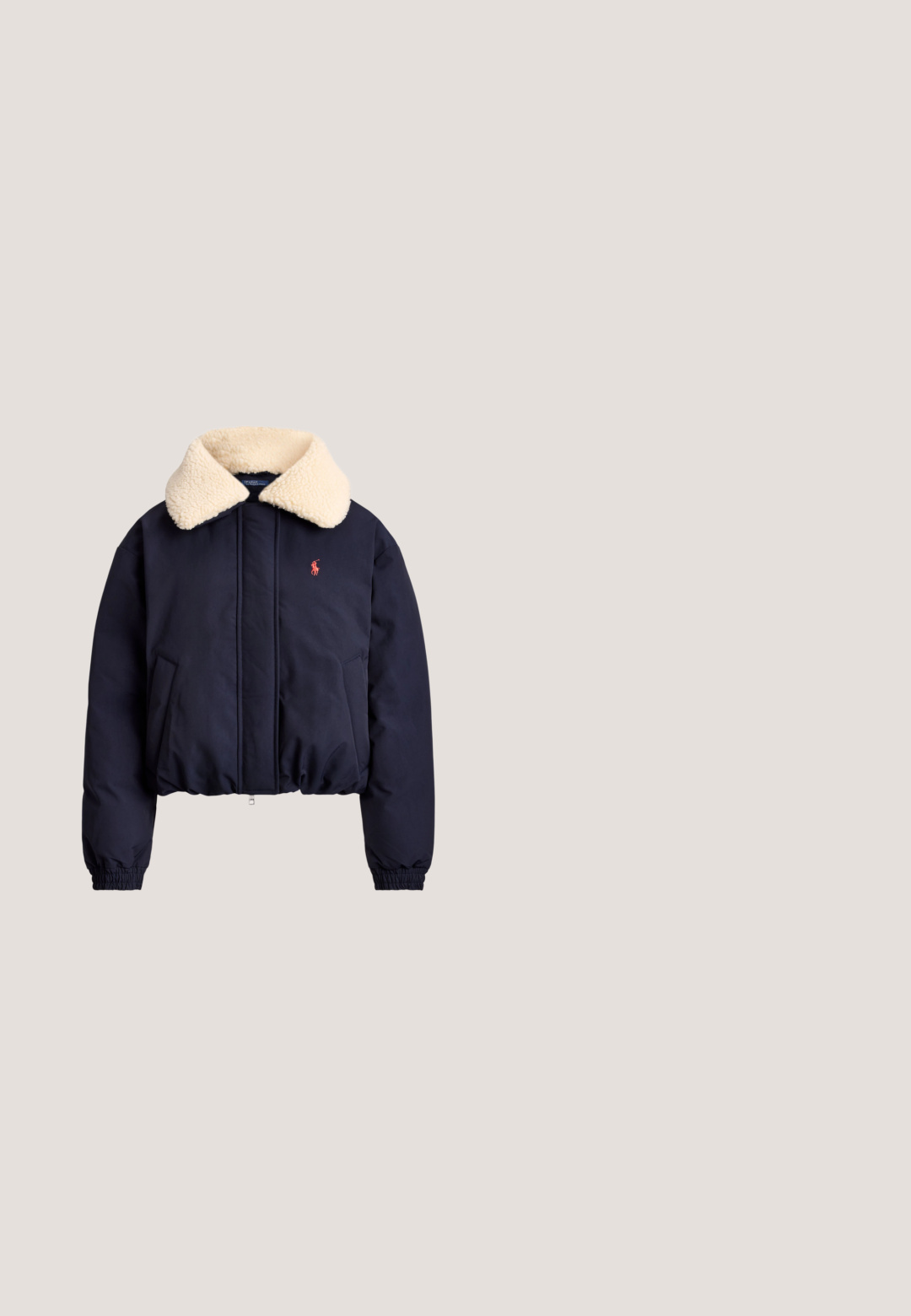 Marineblå jakke med cream sherpa-krave, frontlynlås, sidelommer, elastiske ærmegab og lille rød broderet logo på venstre bryst.; Mørkeblå kabelstrikket sweater med lange ærmer, rund hals, ribbede manchetter og kant, med en lille rød broderet polo-spiller logo på brystet.; Hvid T-shirt med korte ærmer og V-hals med lille marineblåt Polo Ralph Lauren-logo på venstre bryst.; Marineblå joggingbukser med elastisk talje og manchetter, hvid snøre og et lille rødt logo på øverste venstre side.; Hvid lavtop sneaker med snørelukning foran, ruskind- og læderpaneler og en lysebrun gummisål på en hvid baggrund.; Lærred tote bag med marineblå læderdetaljer, der har to lange håndtag, en frontlomme og et lille logo i midten. Beige farve.