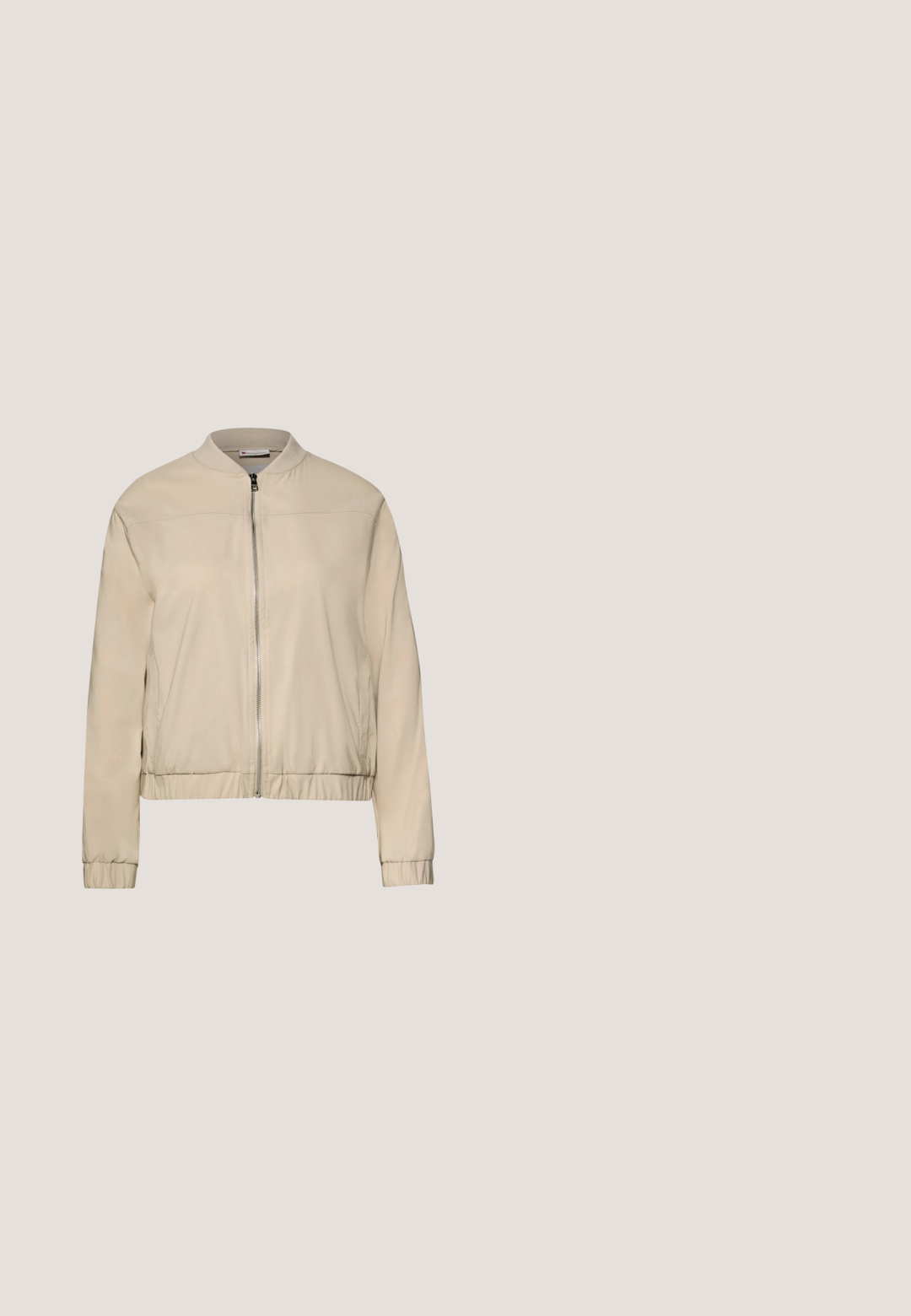 Chaqueta bomber beige claro con una textura suave, puños y dobladillo elásticos. Presenta un cierre frontal y bolsillos laterales, diseño minimalista.; Camiseta de manga corta en color beige con escote en V, hecha de algodón suave, con un corte relajado y un diseño sencillo sin adornos.; Pantalones jogger beige elaborados en tejido suave, con una cintura elástica y cordón, y bolsillos laterales. Diseño de pierna estrecha.; Mocasines de cuero beige con superficie texturizada y un acento dorado, colocados sobre un banco de madera, con una suela blanca gruesa y parte trasera elevada.; Bolso de hombro de cuero texturizado beige con una única correa curva y herrajes y logotipo en color dorado en la parte frontal.; Collar con cadena tipo serpiente en tono oro rosa, con cierre de langosta y cadena de extensión ajustable que termina en un colgante con forma de corazón.