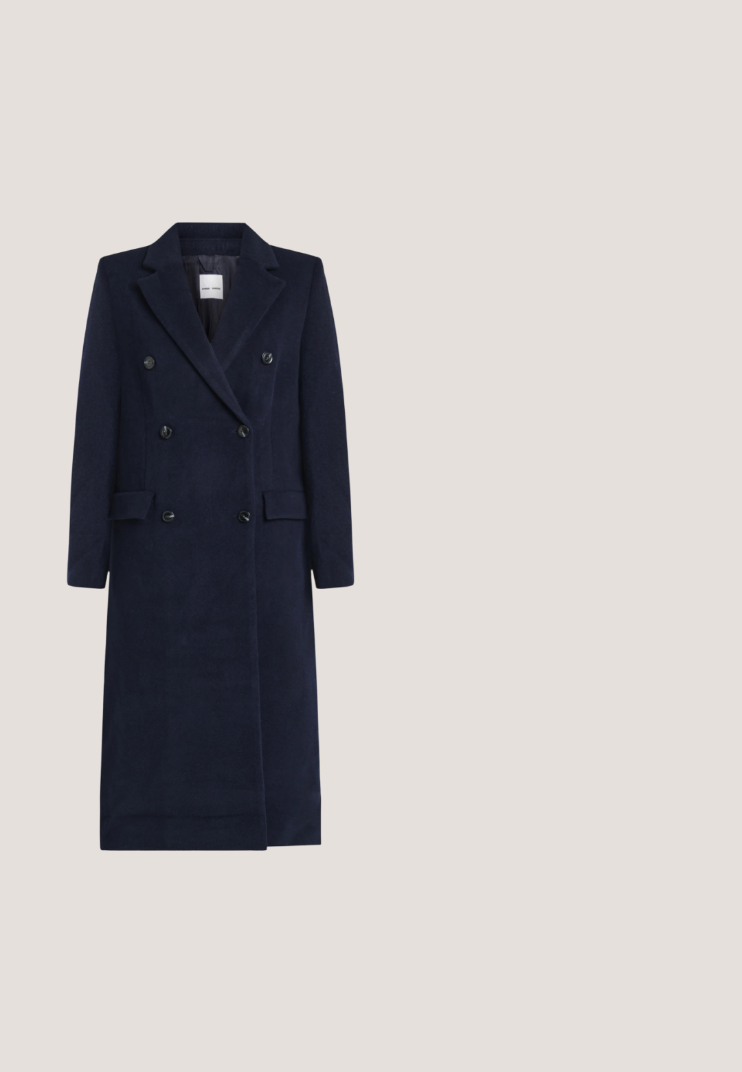 Marineblauwe lange dubbelgeknoopte wollen jas met inkepingen aan de revers, zes knopen, klepzakken en mouwen van volledige lengte.; Marineblauwe blouse met een getextureerd geribbeld ontwerp, een opgevouwen kraag met een strik, en lange mouwen met manchetten met knopen.; Marine-blauwe wijde broek met verticale ribbeltextuur, elastische tailleband en uitlopende zoom. Gemaakt van zachte, comfortabele stof.; Donkerblauwe suède loafer met kwastdetail, lage zwarte hak en mocassinachtige stiksel op een witte achtergrond.; Marineblauwe leren handtas met textuur, voorzien van een bovenste handvat, zilveren kettingriem en een zilveren rechthoekige sluiting, afgebeeld tegen een effen witte achtergrond.; Paar zilverkleurige metalen oorbellen in de vorm van een hoekige letter M met afgeronde stekers op een witte achtergrond.