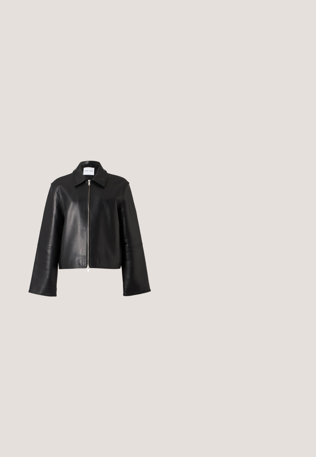 Veste en cuir noire avec une fermeture éclair argentée à l'avant, des manches longues larges et un col pointu sur fond blanc.; Haut noir sans bretelles à pois blancs avec un ourlet peplum volanté, présenté sur un fond clair uni.; Pantalon noir en similicuir taille haute avec jambes larges, passants de ceinture et fermeture avant dissimulée sur un fond uni clair.; STAND STUDIO KELSEY - Mules à talons - black; Sac à main en cuir verni noir de forme rectangulaire, avec de fines poignées et un charm en forme de fleur décoratif. Présente une marque logo à l'avant.; Boucles d'oreilles en argent en forme de créoles, ornées d'un cœur et d'un pendentif en forme de diamant. Texture lisse avec une finition polie.