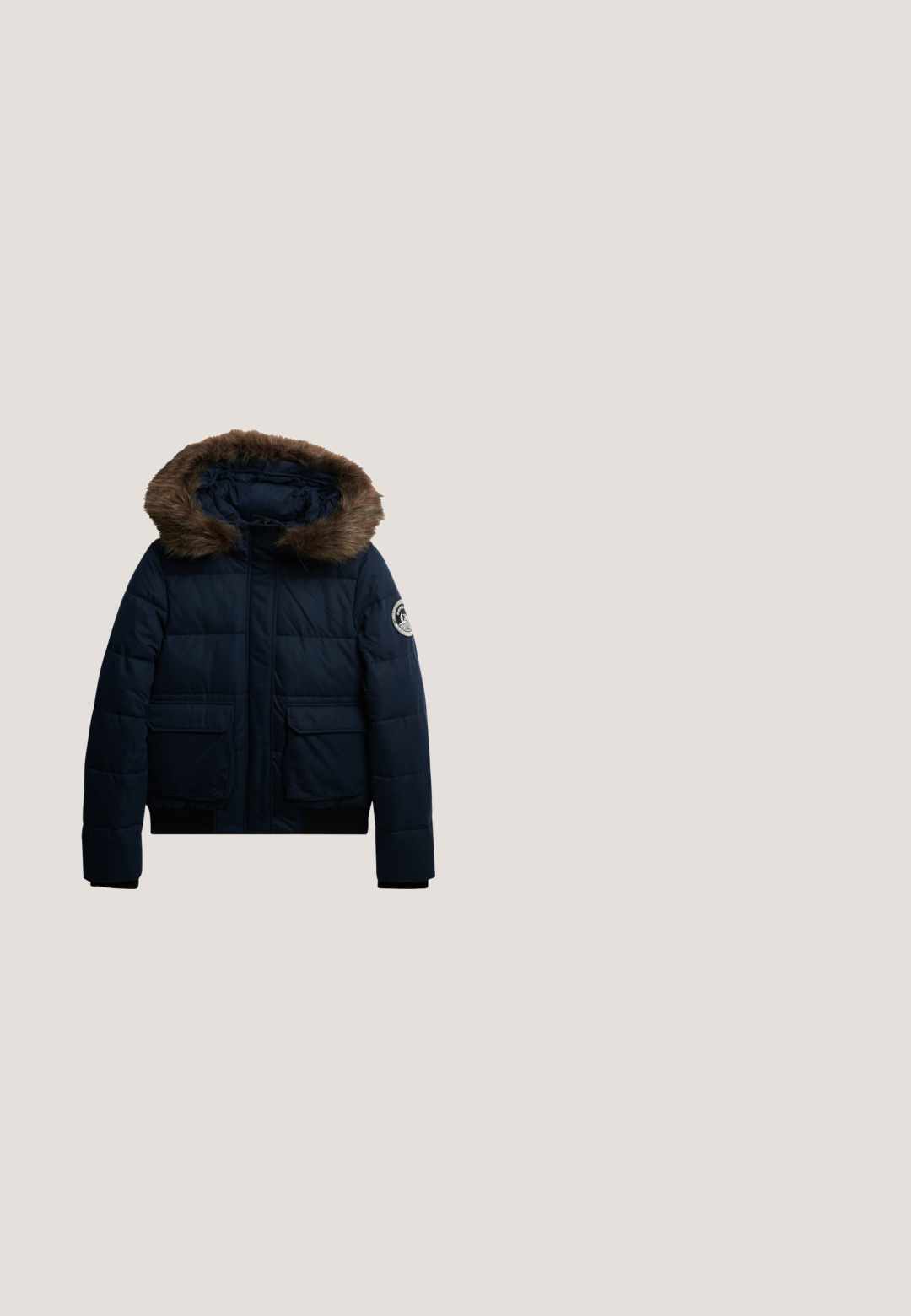 Marineblauwe donsjas met een bont gevoerde capuchon, twee klepzakken aan de voorkant en een ronde logopatch op de linker mouw.; Marineblauwe sweatshirt met ribgebreide manchetten en halslijn, met witte fleece letters die "PARIJS" op de voorkant lezen.; Korte mouwen navy T-shirt met een pinguïn afbeelding in een denim jas, rode hoed en bruine pompons, met een ronde halslijn.; Marineblauwe wijde sweatpants met witte zijkanten, elastische tailleband, trekkoord en het "Super Dry Athletics" logo op de linker dij.; Donkerblauwe lage sneaker met suède en stoffen panelen, vetersluiting aan de voorkant, gestikt zijlogo en witte zool met zwart profiel.; Marineblauwe pluche schoudertas met brede schouderband, voorvak met rits en kleine charme, en ronde metalen logo-detail.