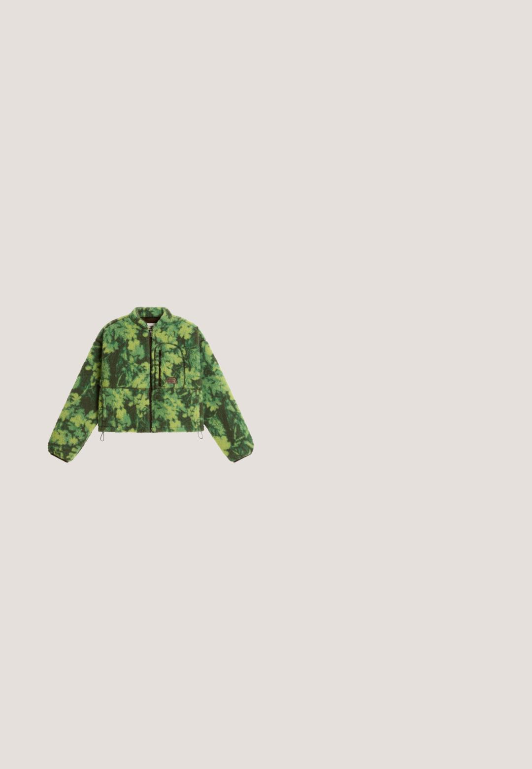 Grüne und dunkelgrüne, camouflagegemusterte Fleecejacke mit durchgehendem Reißverschluss, langen Ärmeln und einer Reißverschlusstasche auf der linken Brustseite.; Olivgrüne Corduroy-Overalls mit weitem Bein, verstellbaren Trägern und einer strukturierten Oberfläche. Einfaches Design, keine sichtbaren Muster oder Beschläge.; Olivgrüner Sport-Sneaker mit beiger gewellter Sohle, grauem Klettverschluss, schwarzen und pinken Akzenten sowie einer Zuglasche an der Ferse.; Lila Kunststoffsonnenbrille mit rechteckigen grünen Linsen. Das Gestell hat ein glänzendes Finish und goldene "Vogue"-Markierung an den Seiten.; Grüne, gepolsterte Schultertasche in Halbmondform mit verstellbarem Riemen und Reißverschluss oben.; Feine Goldkette mit unregelmäßig verteilten aquafarbenen Perlen und kleinen Goldperlen, mit Karabinerverschluss und verstellbarem Verlängerungselement.