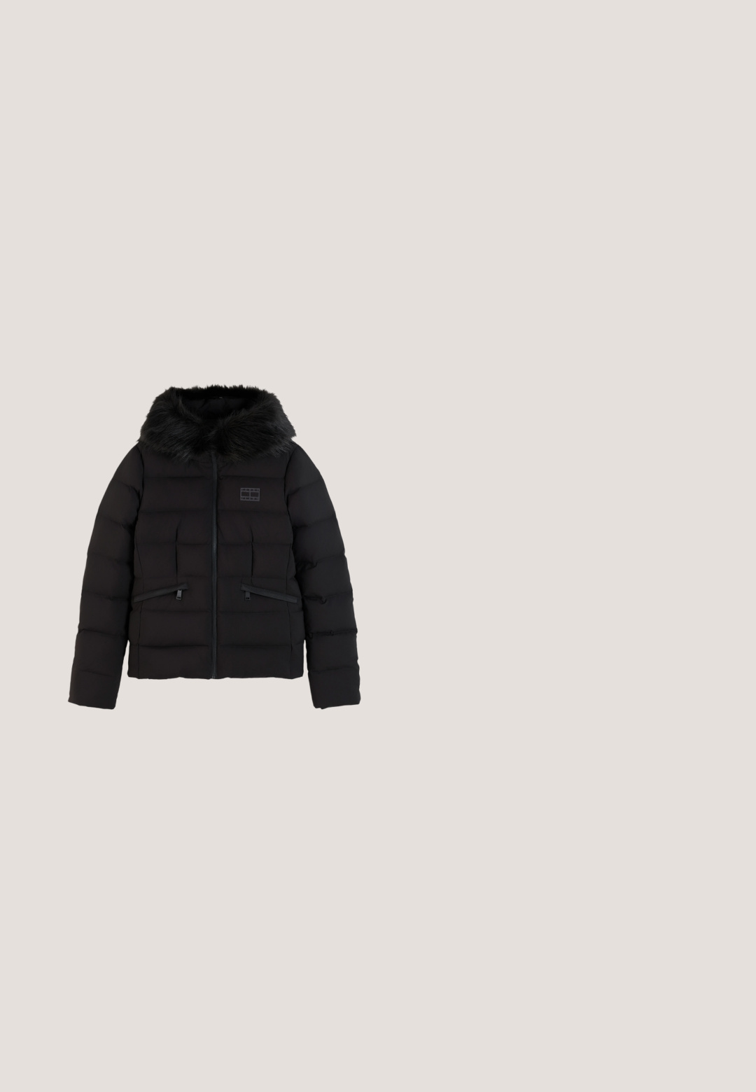 Zwarte donsjas met horizontale stiknaden, voorrits, twee ritszakken en een capuchon gevoerd met zwarte imitatiesuède.; Rood T-shirt met korte mouwen en de tekst "New York City" met een klein Tommy Hilfiger-logo centraal op de borst.; Skinny jeans van donkerblauwe denim, met een middelhoge taille, voorzakken en een ritssluiting met knoop. Soepele textuur, minimale details.; Zwarte low-top sneakers van glad materiaal, met dikke veters, een gestructureerde zool en een klein logo aan de zijkant en op de tong.; Zwarte rechthoekige tas van glad weefsel. Heeft dubbele handvatten, een verstelbare schouderriem en een opvallende logopatch in rood, wit en blauw.; Paar glanzende gouden oorringen met een vierkante vorm en een klein rood, wit en zwart gestreept detail bij de sluiting op een witte achtergrond.