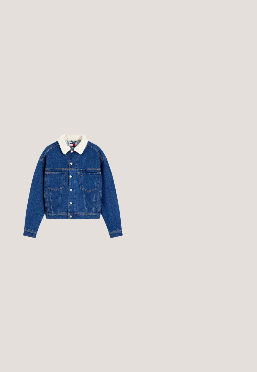 Blauwe spijkerjas met witte sherpa kraag, knopen aan de voorkant, twee borstzakken en lange mouwen.; Witte polo met korte mouwen met dunne horizontale zwarte en rode strepen, rode accenten op de kraagranden en een klein logo op de linkermouw.; Lichtblauwe denim jeans met een rechte, losse pasvorm, voorzien van contrasterende paneeldetails en een vijf-pocket ontwerp. Knopen vloogsluiting.; Witte lage sneaker met gouden accenten en beige zool, zwevend in de lucht boven een buitenoppervlak van patroon van hout en steen.; Zwarte leren handtas met gouden rits en beslag, enkele handgreep en bijpassend zwart leren etui bevestigd.; Zilverkleurige hoepel oorbellen met een glad, rond ontwerp en een kleine accentstreep in rood, wit en blauw. Veilige studsluiting.