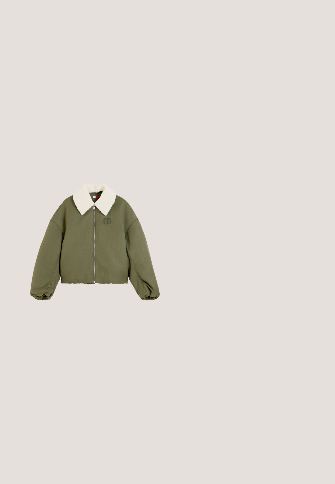 Veste courte vert olive avec manches oversize, col en polaire blanc, fermeture éclair frontale et poignets élastiques.; Pull en tricot noir à manches courtes avec un col rond, arborant un petit logo brodé en rouge, blanc et bleu sur la poitrine.; Jeans métalliques dorés au design droit, cinq poches, quincaillerie en cuivre et finition texturée. Présente une taille en denim bleu.; Bottine en cuir noir au design épuré, à bout rond, avec des coutures texturées en haut et un talon bloc. Équipée d'une fermeture éclair et d'une tirette.; Sac à main en cuir noir de forme rectangulaire, base plate, deux bandoulières et un petit logo sur le devant. Texture lisse.; Boucles d'oreilles en argent avec un design lisse et arrondi, accentuées par une petite rayure rouge, blanche et bleue. Fermoir à tige sécurisé.