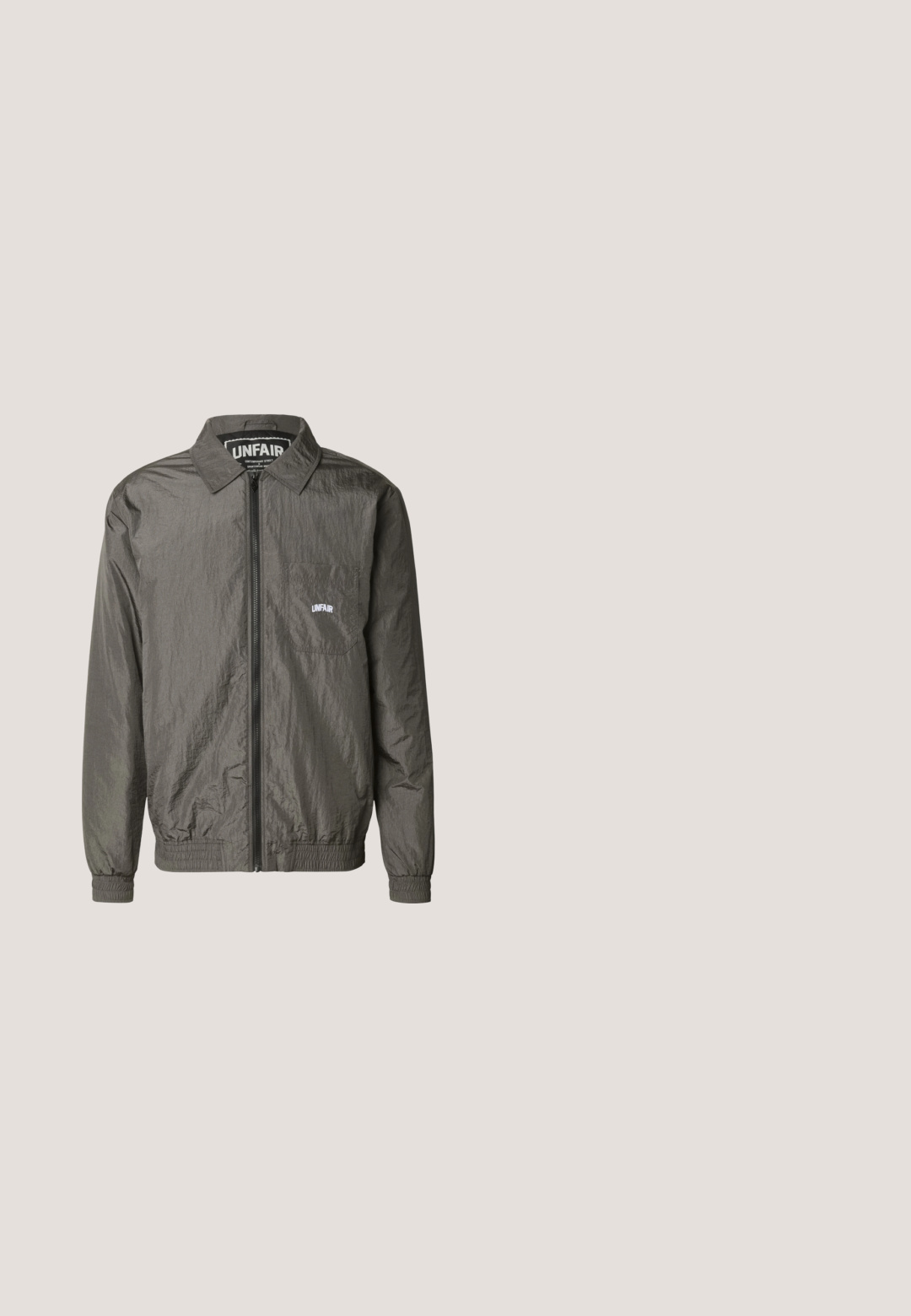Donkergrijze lichte jas met rits en kraag, elastische manchetten en zoom, borstzak met wit "UNFAIR" logo op de zak en binnenin de kraag.; Zwart Adidas T-shirt met korte mouwen en ronde hals, subtiel merklogo op de borst en gestikte paneeldetails op de schouders en zijkanten.; Zwarte sportieve shorts met een elastische tailleband, voorzien van witte zijstrepen en een gladde stofstructuur. Geen extra versieringen.; Zwarte waterdichte rubberlaars met een verstelbare gesp, een gestructureerd oppervlak, een licht gebogen vorm en een robuust profiel voor grip.; Zonnebril met grote, gebogen donkergrijze lenzen, een zwart plastic montuur, met uitsparingen op de pootjes voor ventilatie en comfort.; Zwarte rechthoekige toilettas met vooraan een horizontale ritssluiting en een zijriem, afgebeeld op een witte achtergrond.