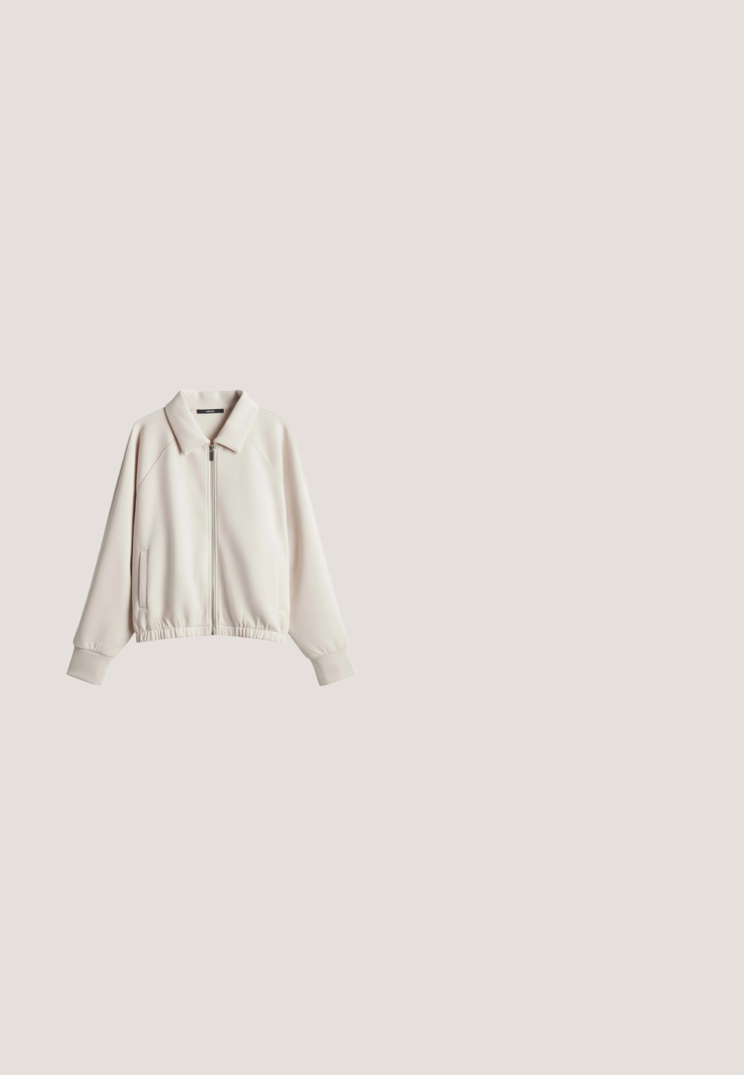 Beige langärmelige Jacke mit Reißverschluss, Kragen, elastischem Saum, Seitentaschen und gerippten Bündchen, flach auf weißem Hintergrund ausgelegt.; Kurzärmliges, elfenbeinfarbenes, geripptes T-Shirt. Runder Ausschnitt, weiche Textur, taillierte Passform und ein dezentes Markenlabel am Ausschnitt.; Beige weit geschnittene Hose mit elastischem Bund und Seitentaschen, vorne mit Falten und einem lockeren, lässigen Sitz.; Weißer Ledersneaker mit beigen Schnürsenkeln und einem diagonalen Metallstreifen in Roségold an der Seite, flache Sohle, niedrig geschnittenes Design.; Beige Leder-Schultertasche mit glatter Textur, breitem Träger und dezentem goldfarbenem Logo nahe der unteren Mitte.; Goldfarbenes Armband mit interlocking Ringen; einer glatt, einer gedreht. Zartes Design mit einem Karabinerverschluss und verstellbarer Länge.