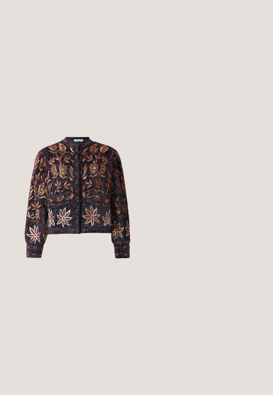 Veste bomber brodée en marine avec des motifs floraux complexes en or, bordeaux et argent. Dotée d'un col rond et de poignets ajustés.; Blouse en dentelle blanche à manches longues, avec épaules bouffantes, motif floral, ourlet à volants et col rond.; Jupe noire avec un motif floral vert, dotée de bords à volants et de plis. Fabriquée en tissu léger, offrant une silhouette fluide.; Sandales à talons dorés avec un design plateforme, dotées d'une texture nouée sur la bride des orteils et d'une fine bride de cheville avec une boucle.; Pochette en forme de nœud en ton argent, ornée de strass transparents et d'un fermoir en cristal sur le dessus.; Broche en or ornée de quatre formes de fleurs composées de pierres précieuses facettées bleues, vertes et transparentes disposées en un motif symétrique.